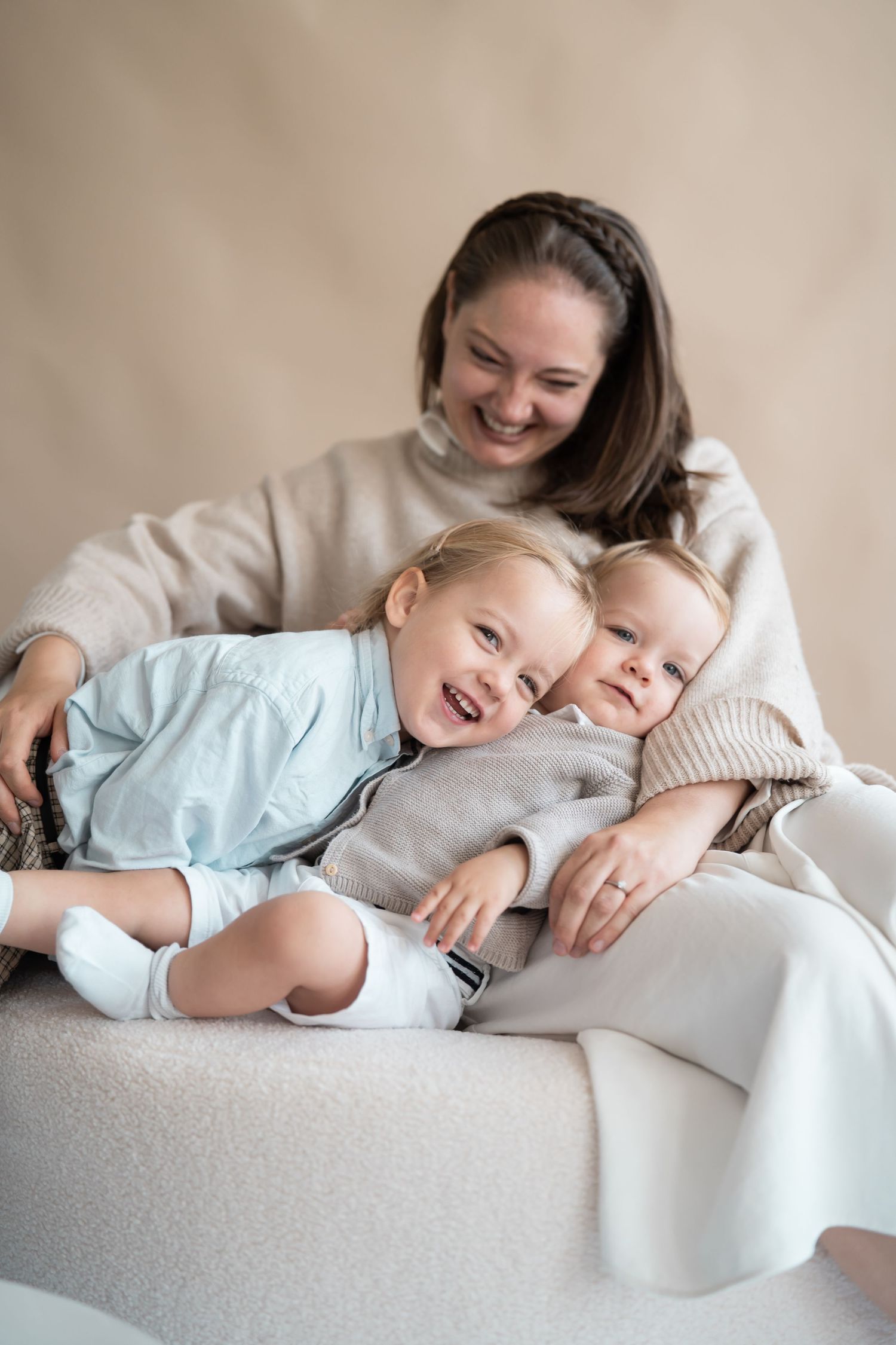 Mutter mit zwei kleinen Kindern in inniger Umarmung bei einem natürlichen Familien Fotoshooting im hellen  modernen Studio