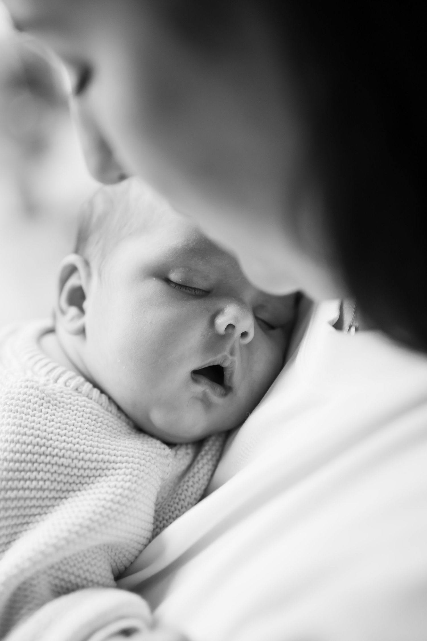 Babyfotografie Berlin – schwarz-weiß Nahaufnahme eines schlafenden Neugeborenen, zeitlose Homestory aufnahme, The Elephant Lab
