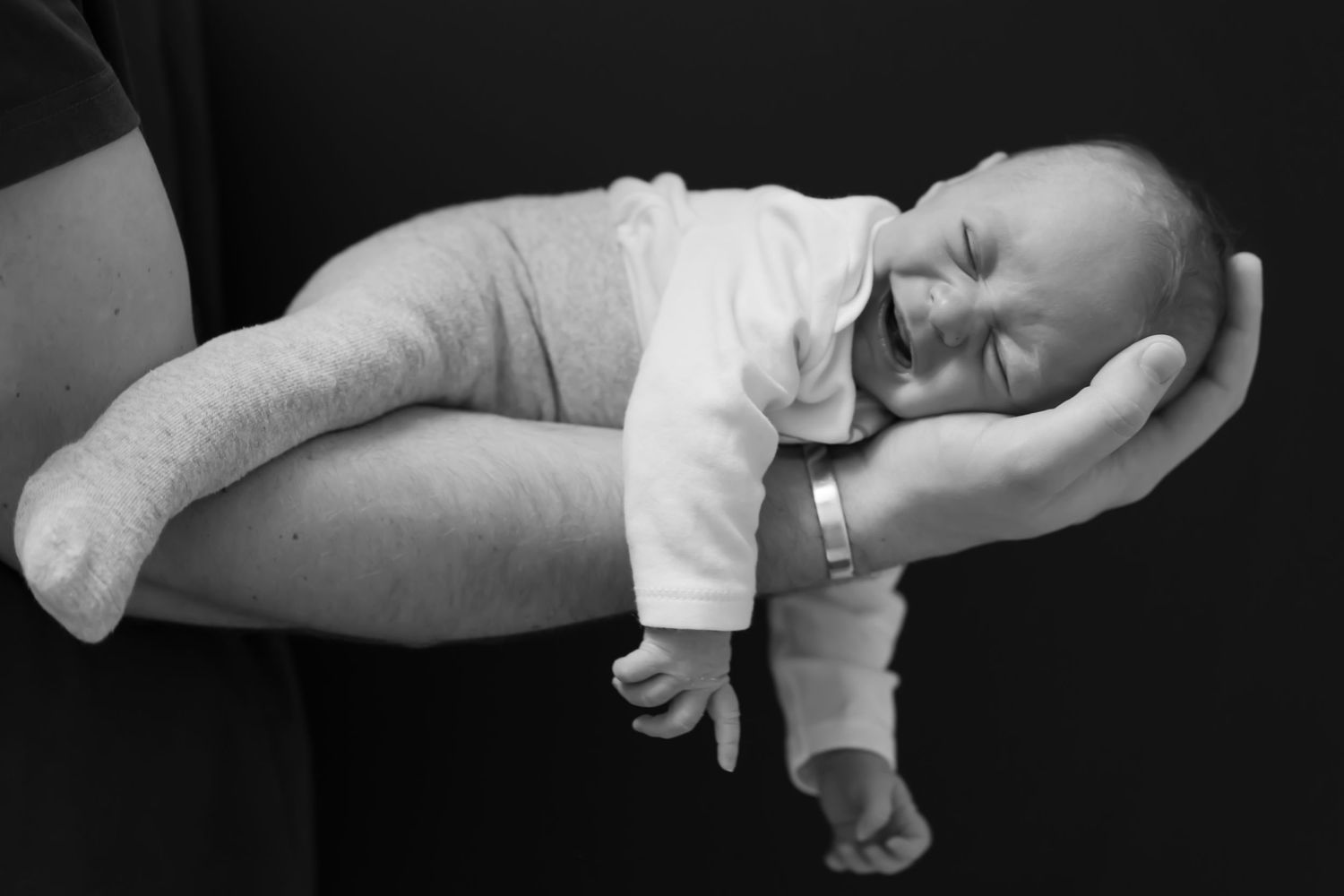 Neugeborenen Fotoshooting Berlin – schlafendes Baby liegt in den Händen eines Elternteils, schwarz-weiß, The Elephant Lab Charlottenburg