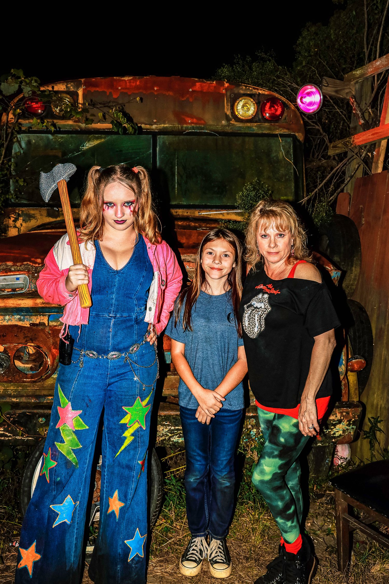 Children wearing matching denim outfits with colorful star decorations stand together in a casual outdoor setting.