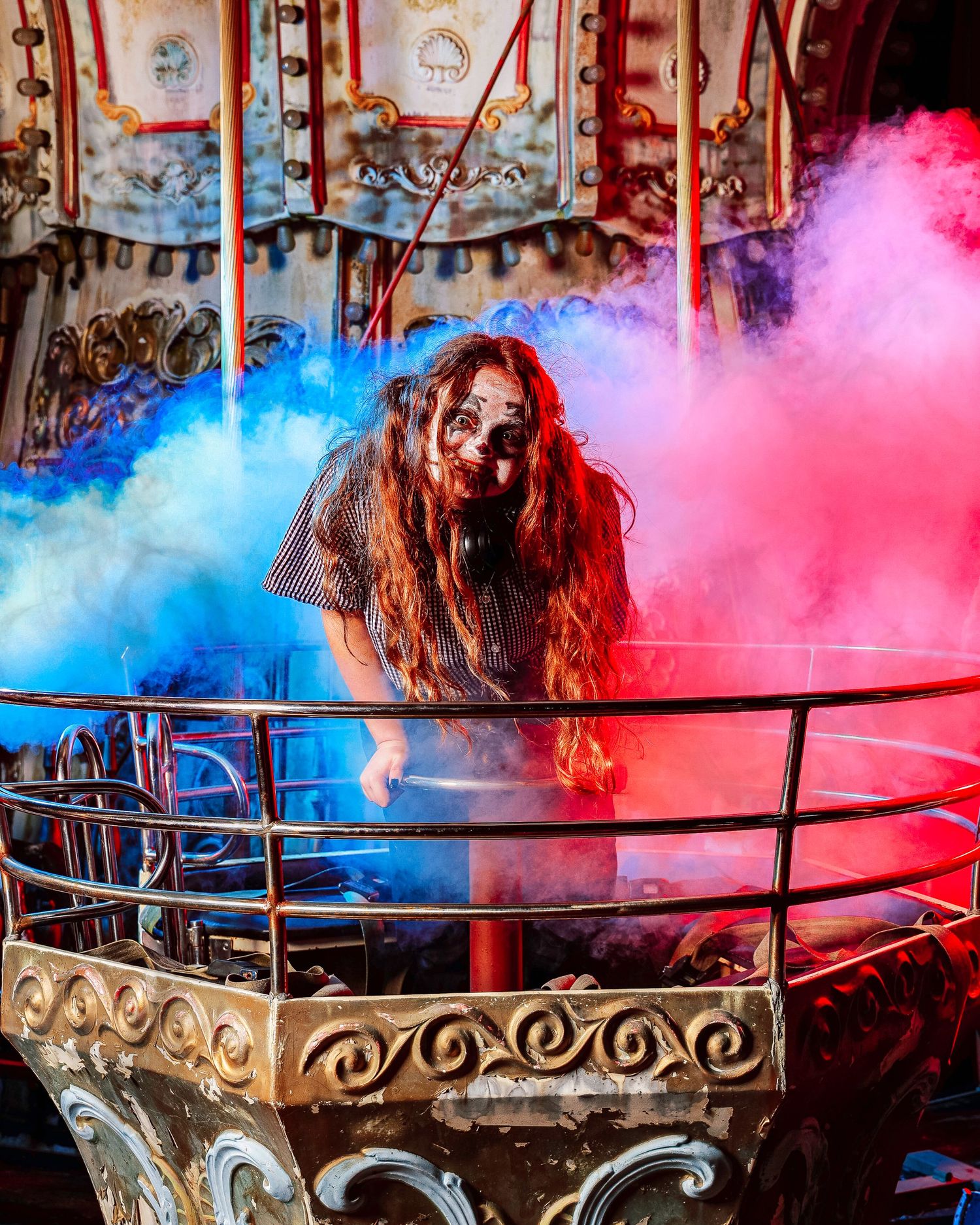 Colorful pink and blue smoke effects create a dramatic atmosphere on a dark stage with ornate railing details.