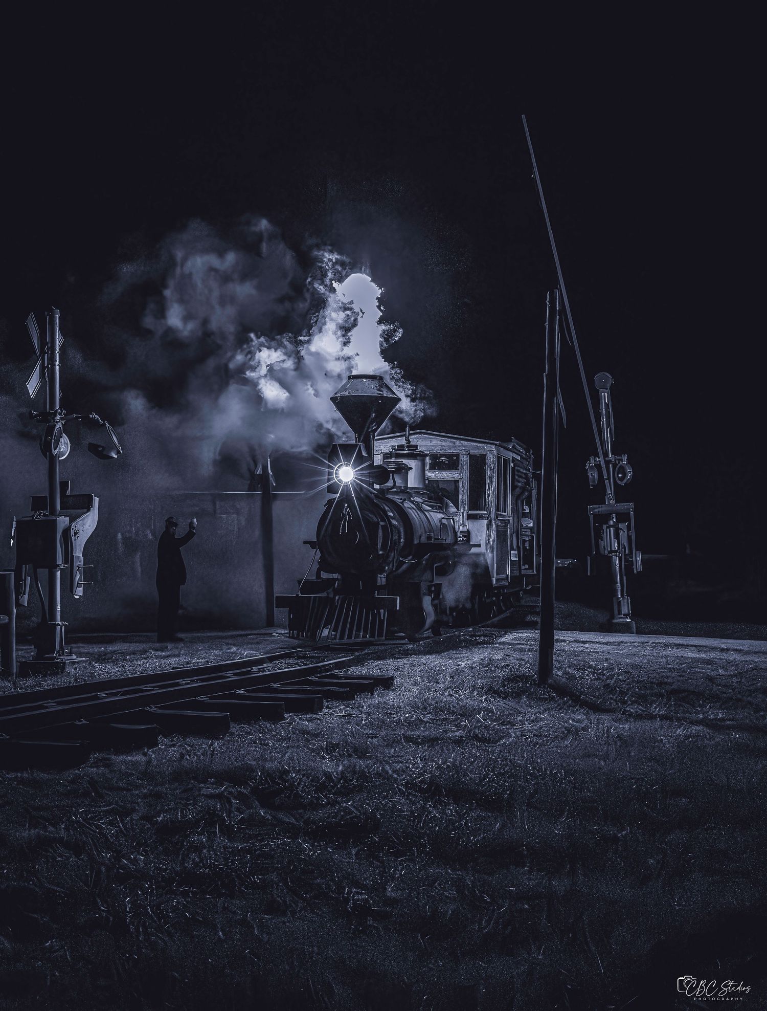 Dramatic black and white nighttime scene of steam locomotive at railway station.