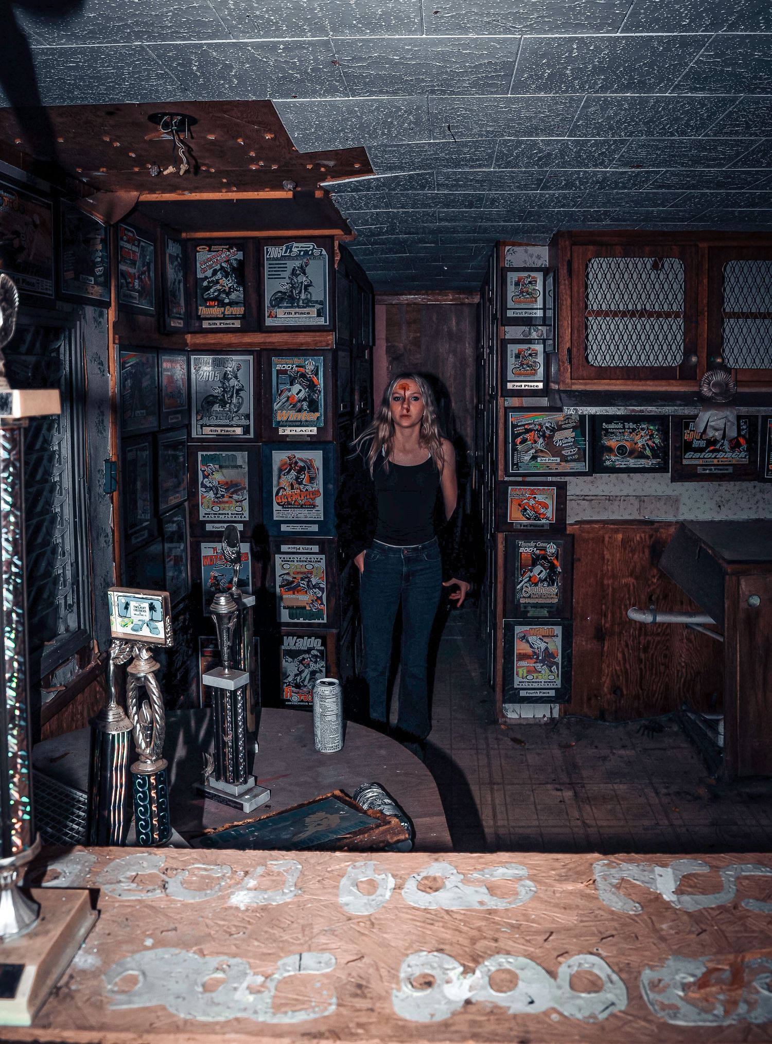 A dark underground room with wooden panels and framed photographs on walls showing an industrial or urban setting.