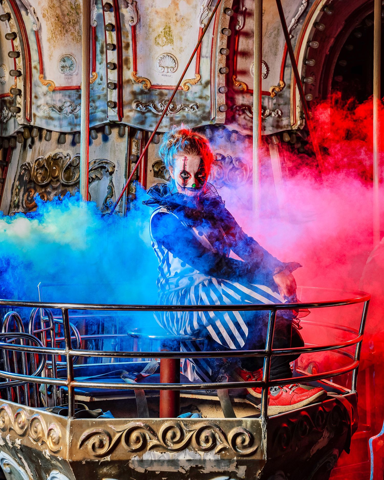 Colorful red and blue smoke effects create an atmospheric display against an ornate metal railing in a dimly lit setting.