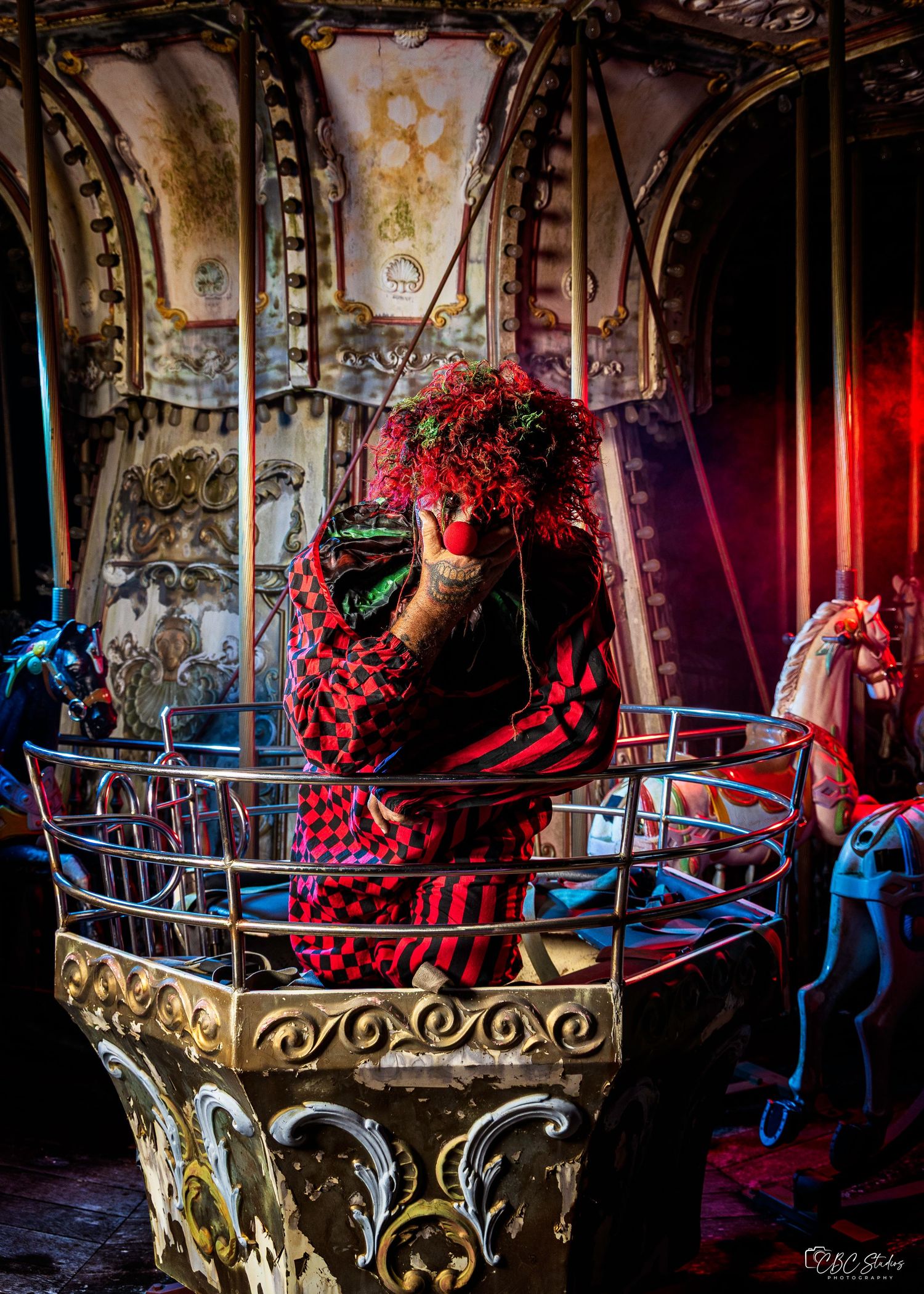 A person in a red plaid shirt photographs flowers on an ornate vintage carousel with decorative gold details and blue accents.