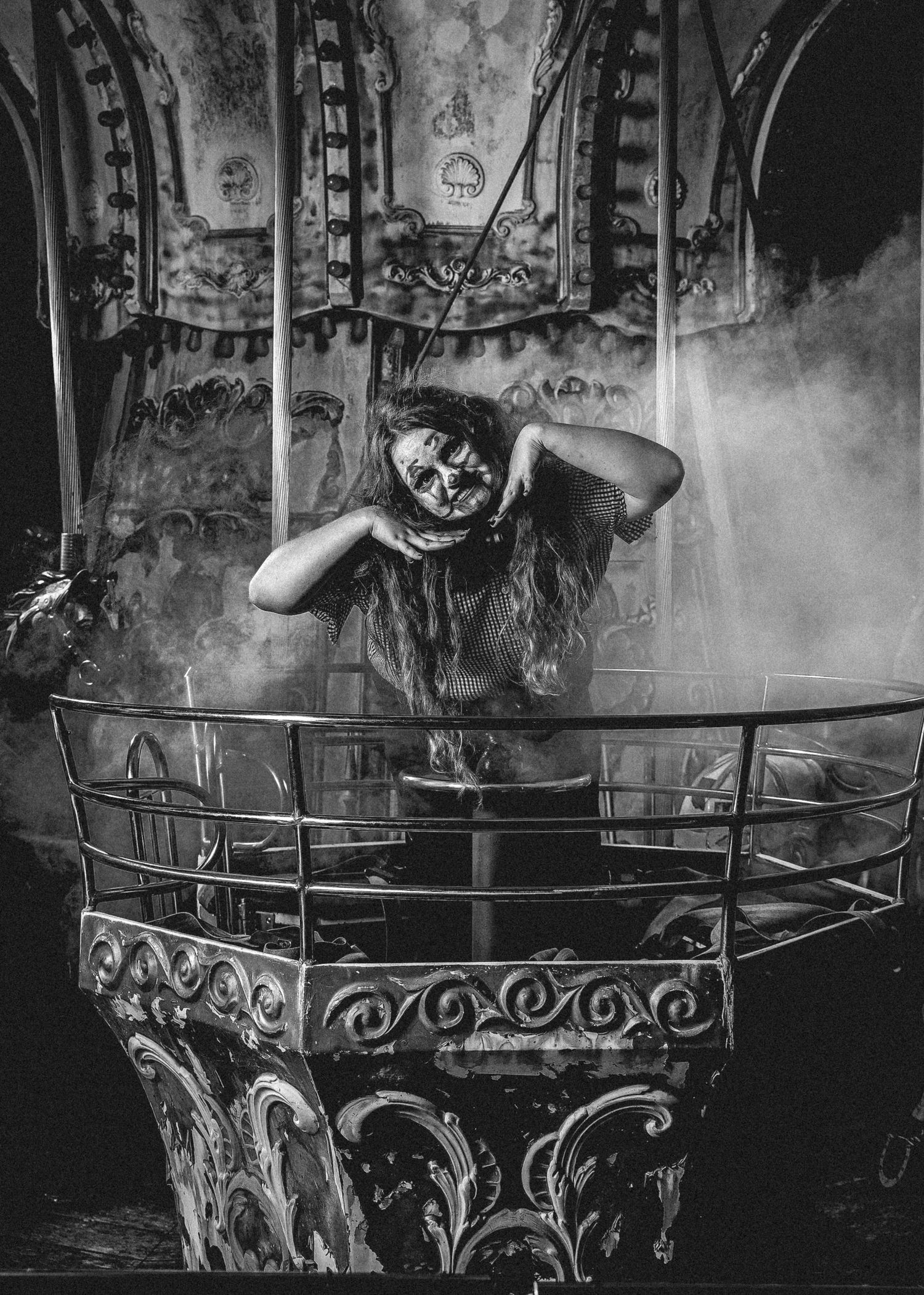 Black and white image of an ornate metal carousel railing with fog or smoke creating a mystical atmosphere.
