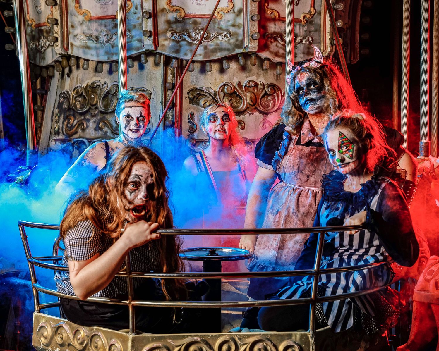 Carousel horses illuminated by dramatic red and blue lighting in a vintage amusement park setting.