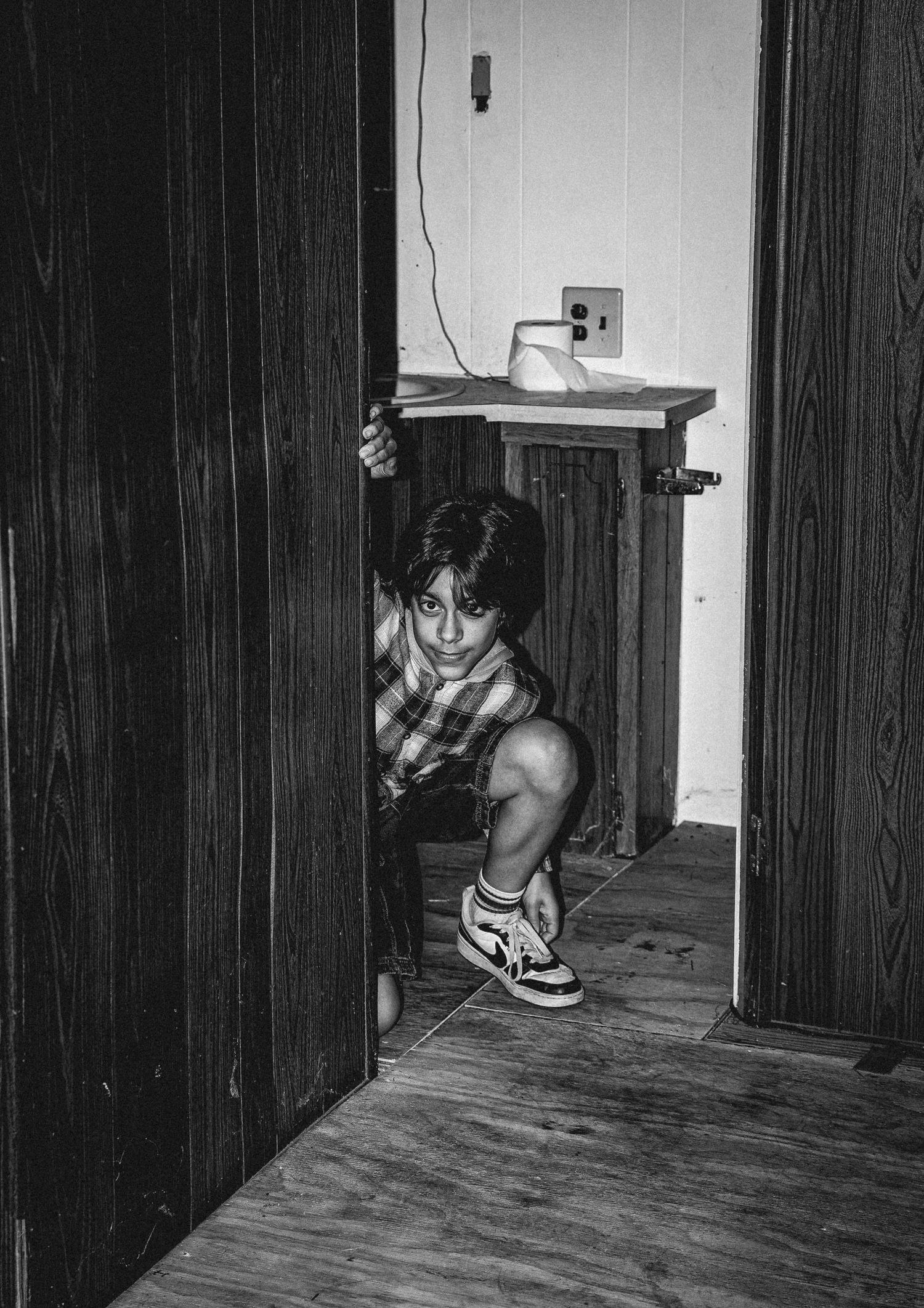 Black and white photo series showing a person crouched down peeking through doorways in a dark hallway.