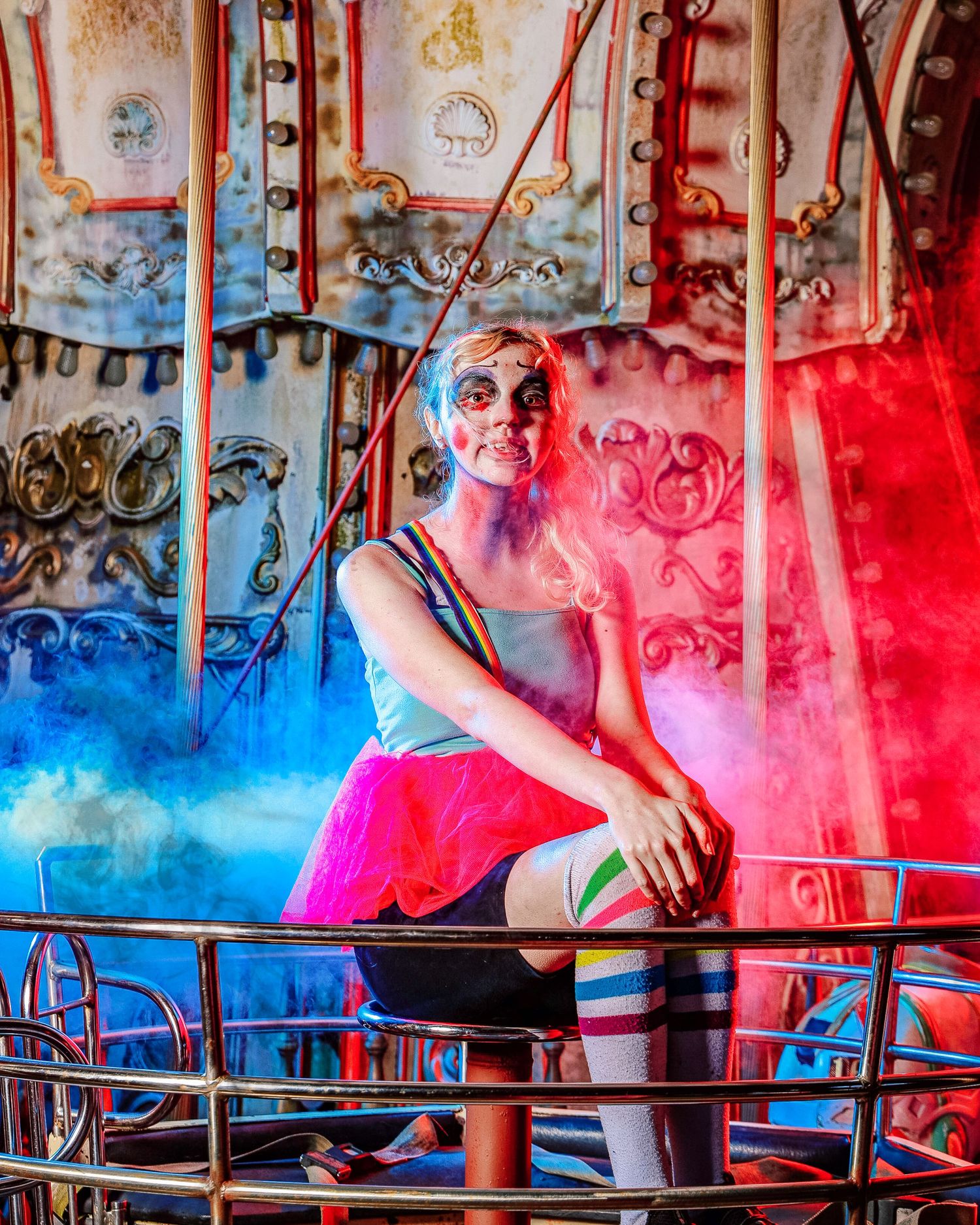 Carousel horses illuminated by dramatic red and blue lighting effects create a magical carnival atmosphere.