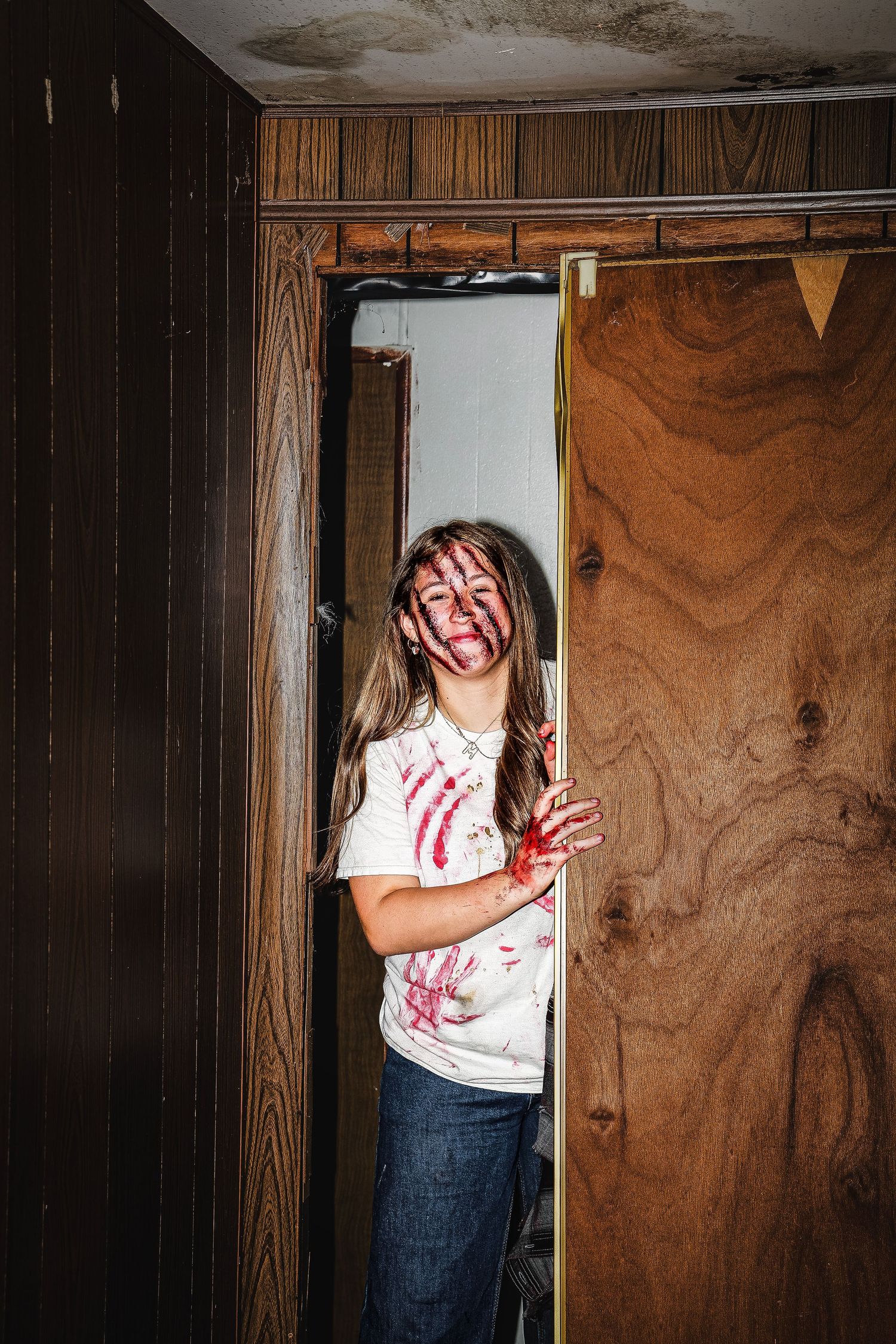 A sequence of five images showing a person in a blood-stained white shirt against a dark wooden wall.
