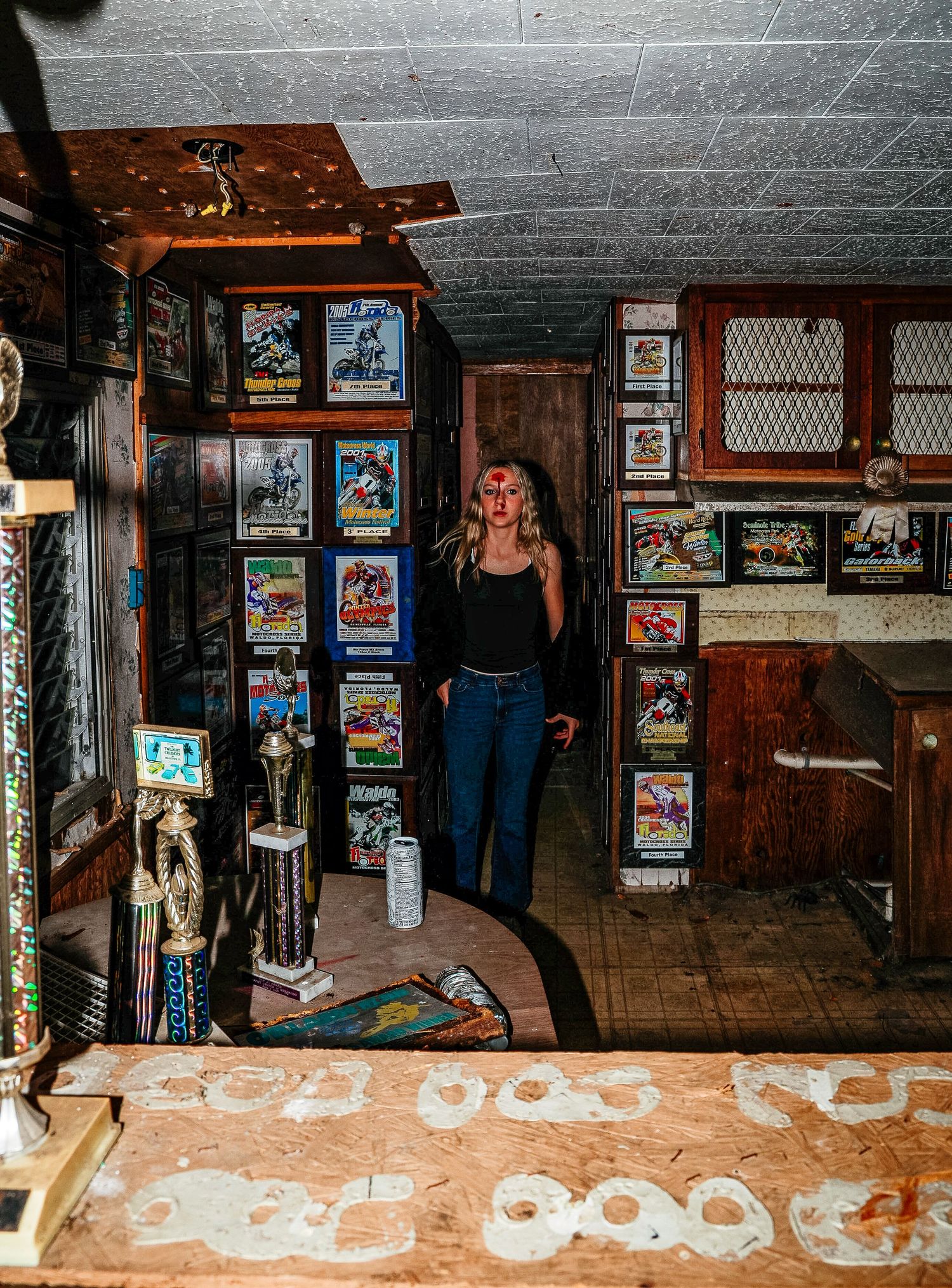 Vintage movie posters line the walls of a dimly lit basement room with a retro bar counter and wooden decor.