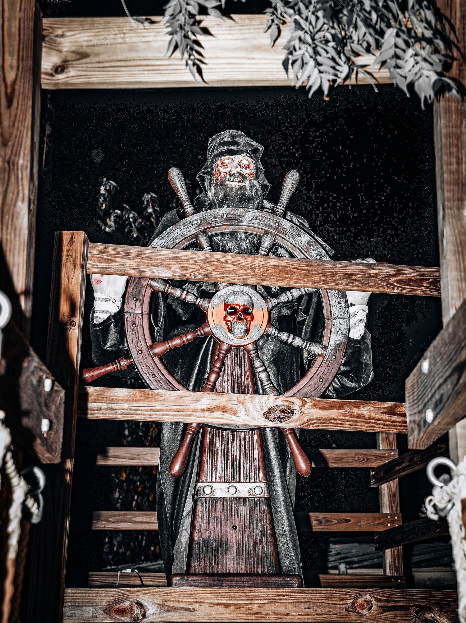 Vintage spinning wheel display with wooden frame and spokes in rustic barn setting.