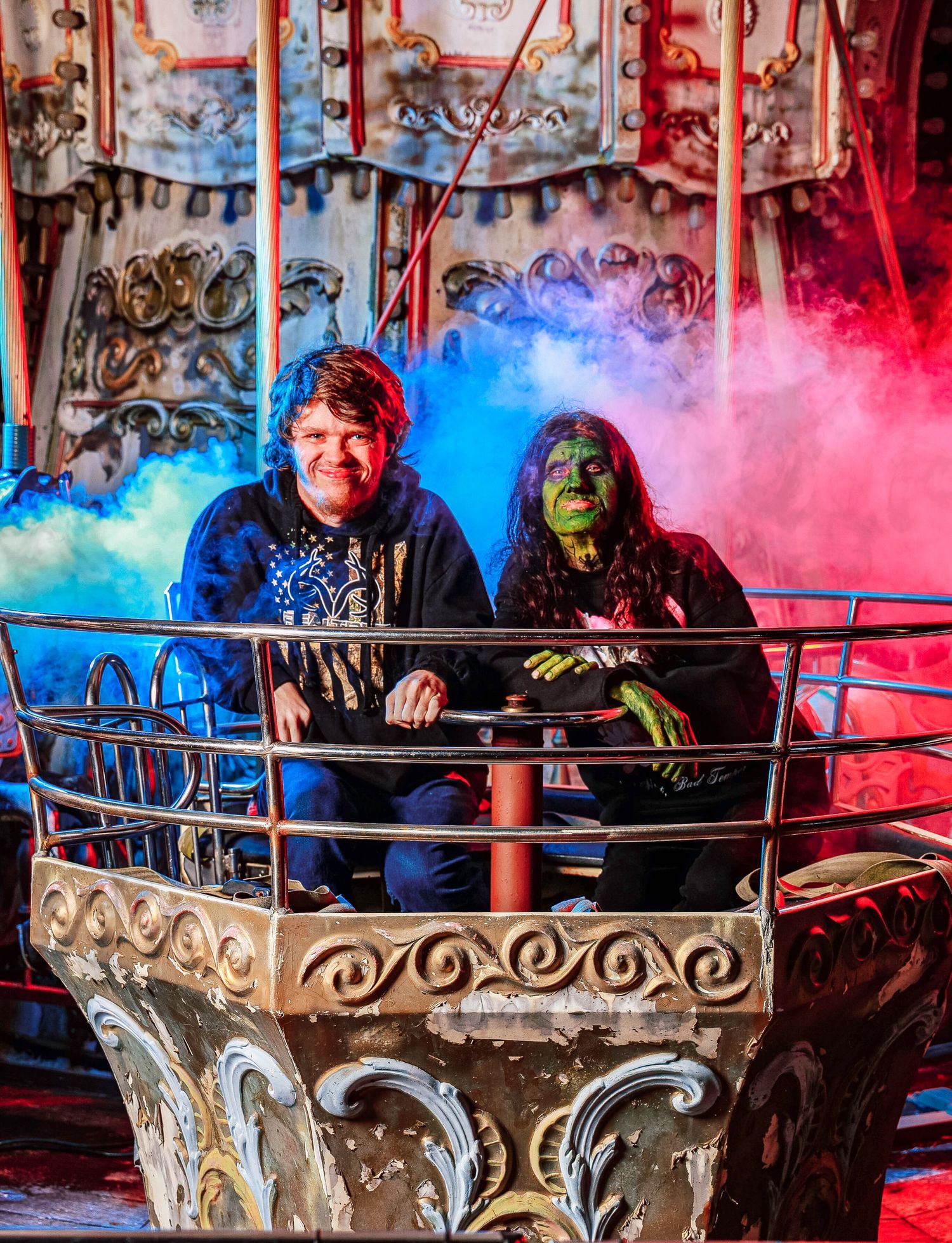 A series of four photos showing a couple enjoying a themed amusement park ride with colorful smoke effects.