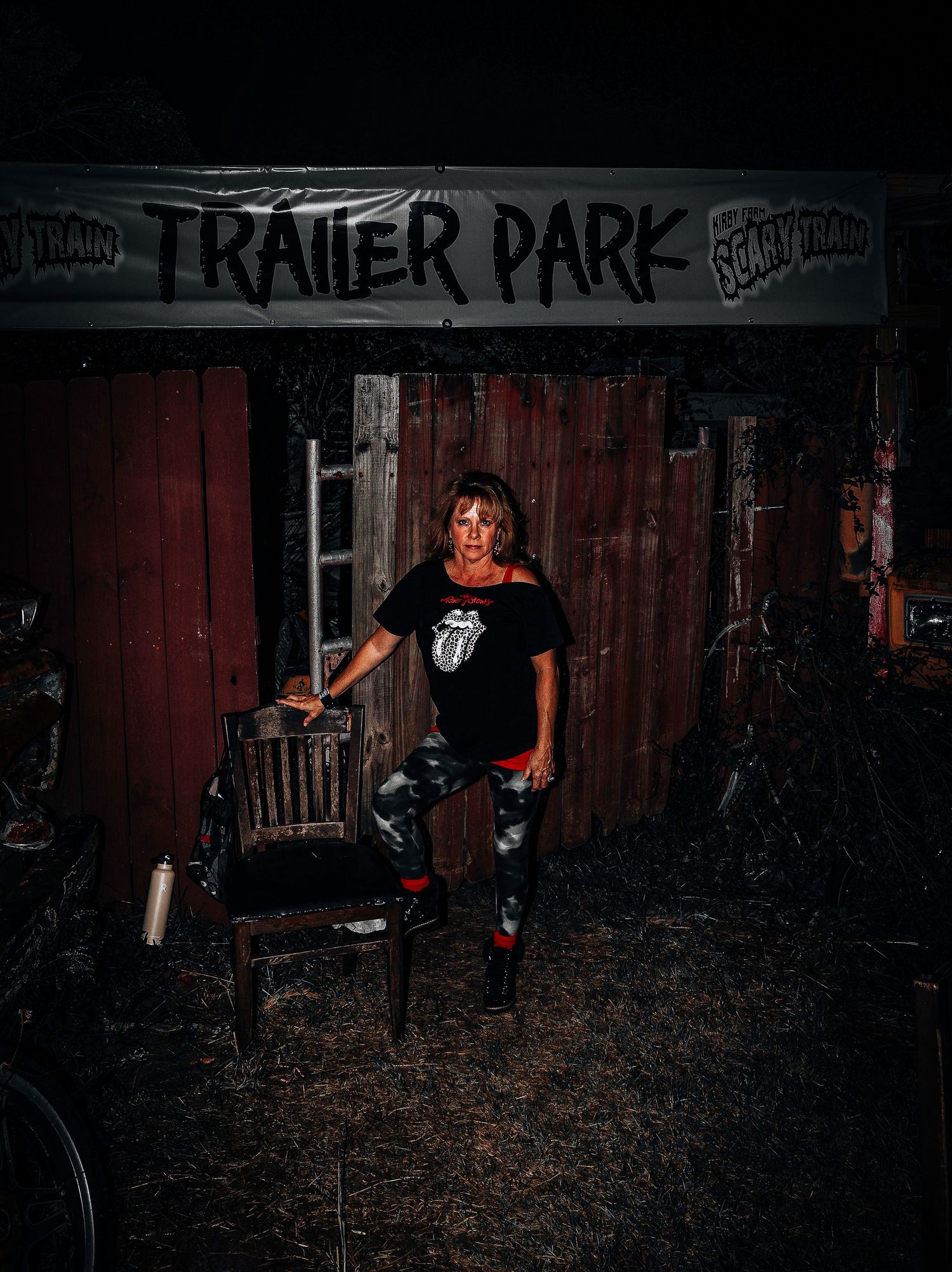 Dark moody portrait against red wooden wall with 'Trailer Park' graffiti text above in dramatic night lighting.