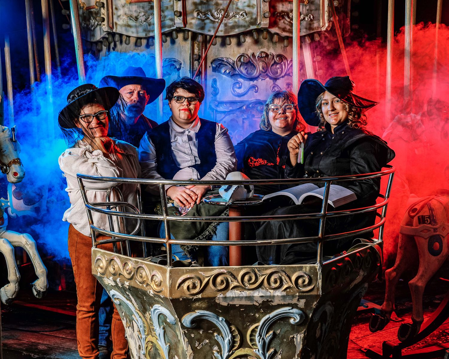 Guests enjoying a dark amusement park ride with dramatic red and blue lighting effects.