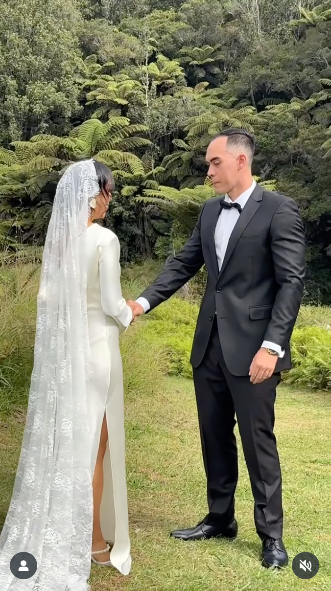Wedding couple poses against lush green forest backdrop with ferns and tropical foliage