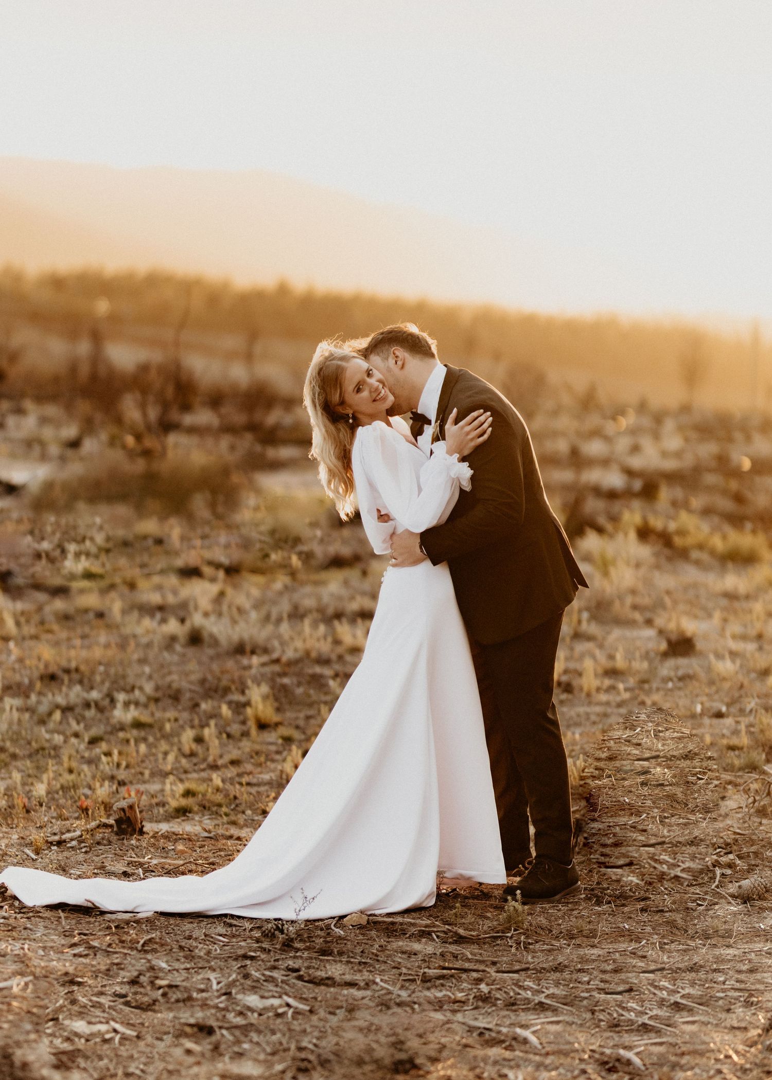 Elegant wedding photo series featuring a long white dress train and romantic poses at sunset.