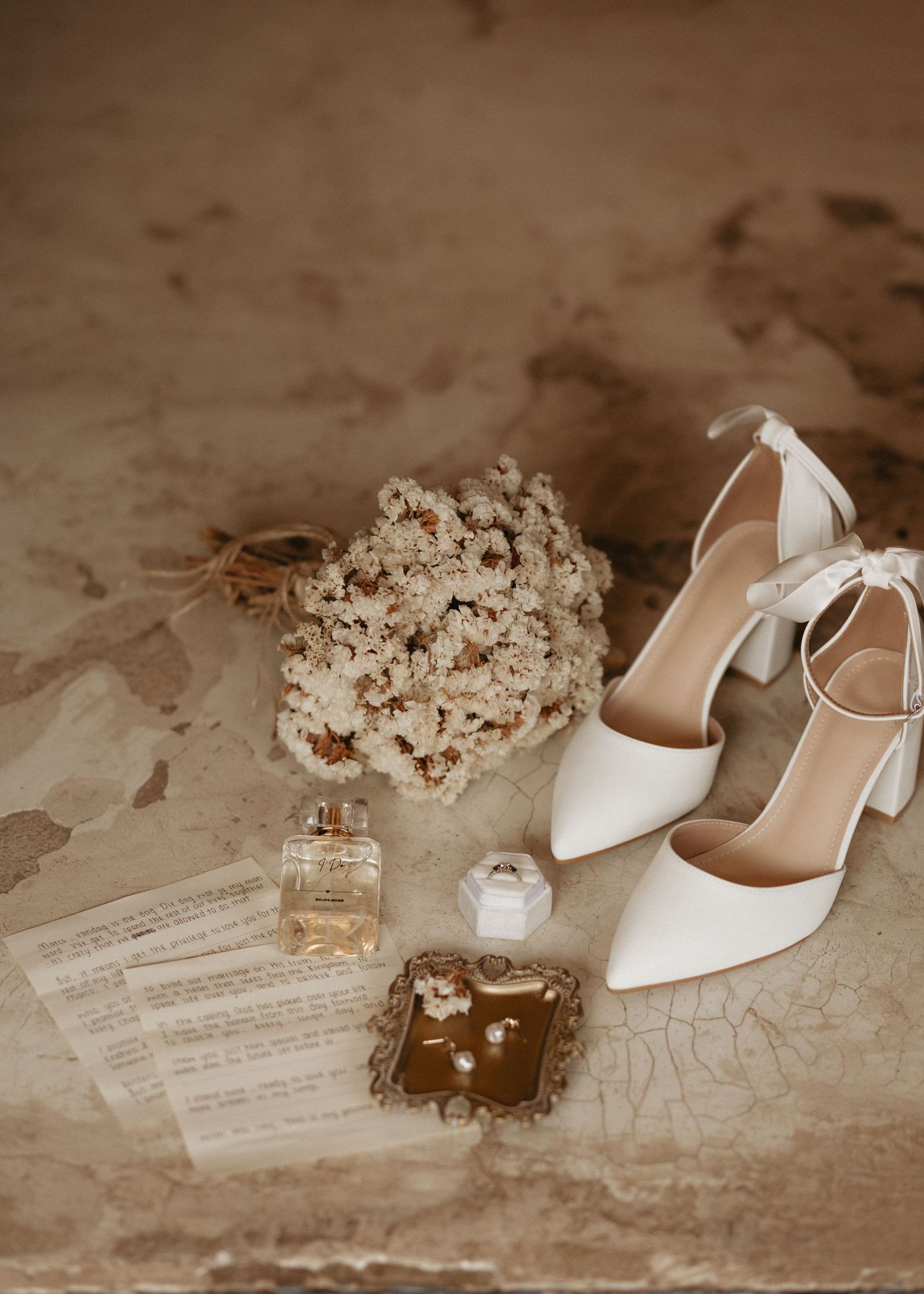 Elegant white wedding shoes displayed with delicate floral arrangements and vintage decor in sepia tones.