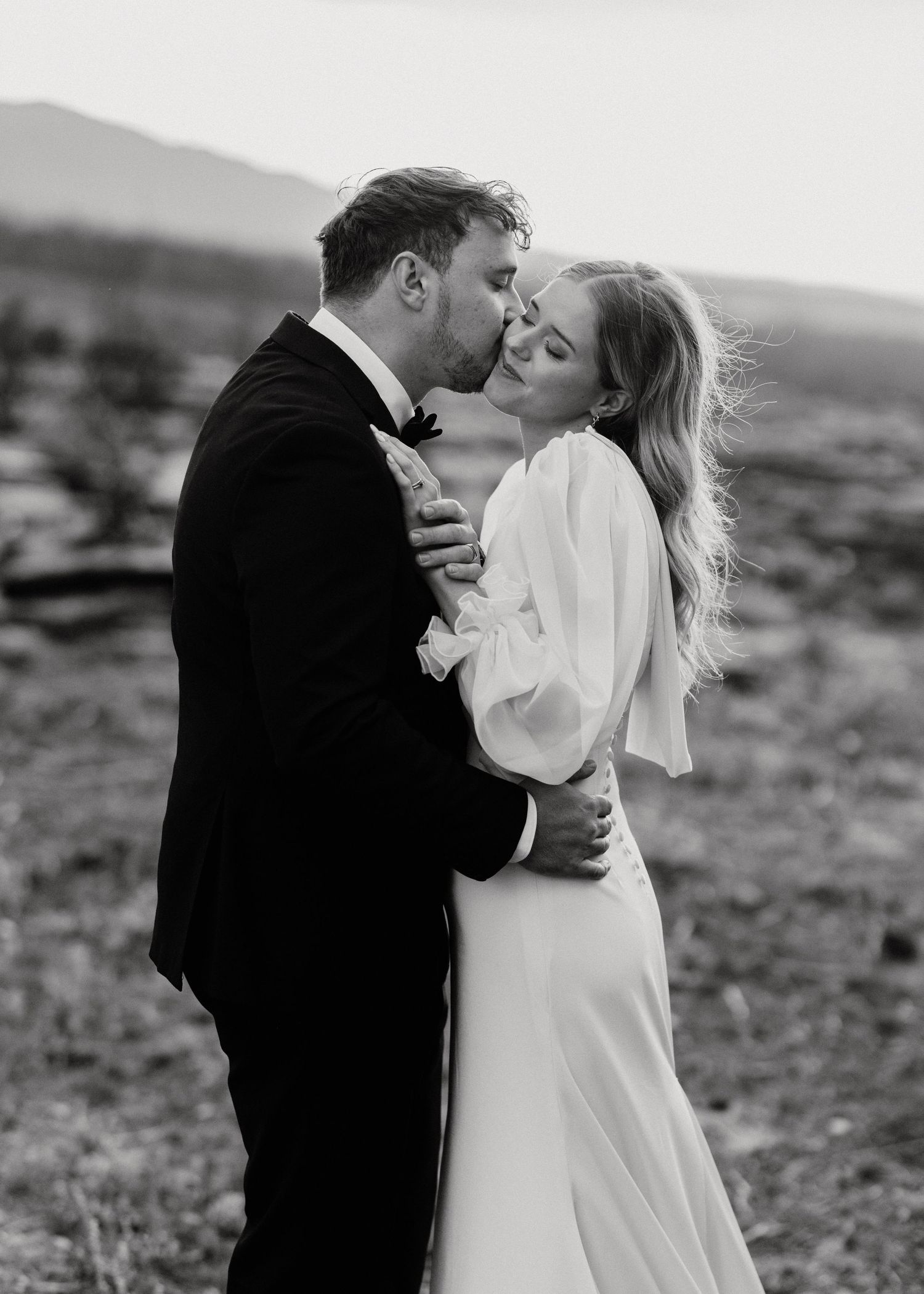 Black and white desert wedding photo captures romantic moment between bride and groom.