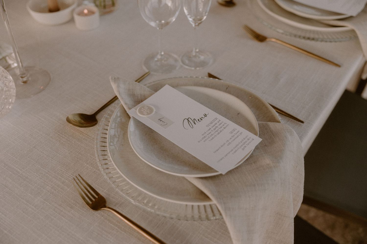An elegant place setting with wine glasses and menu card on a white tablecloth.