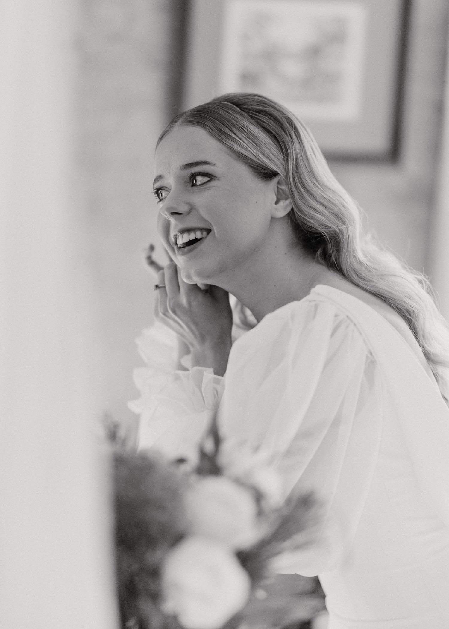 A joyful moment captured in black and white showing a candid smile in a white top with natural lighting.
