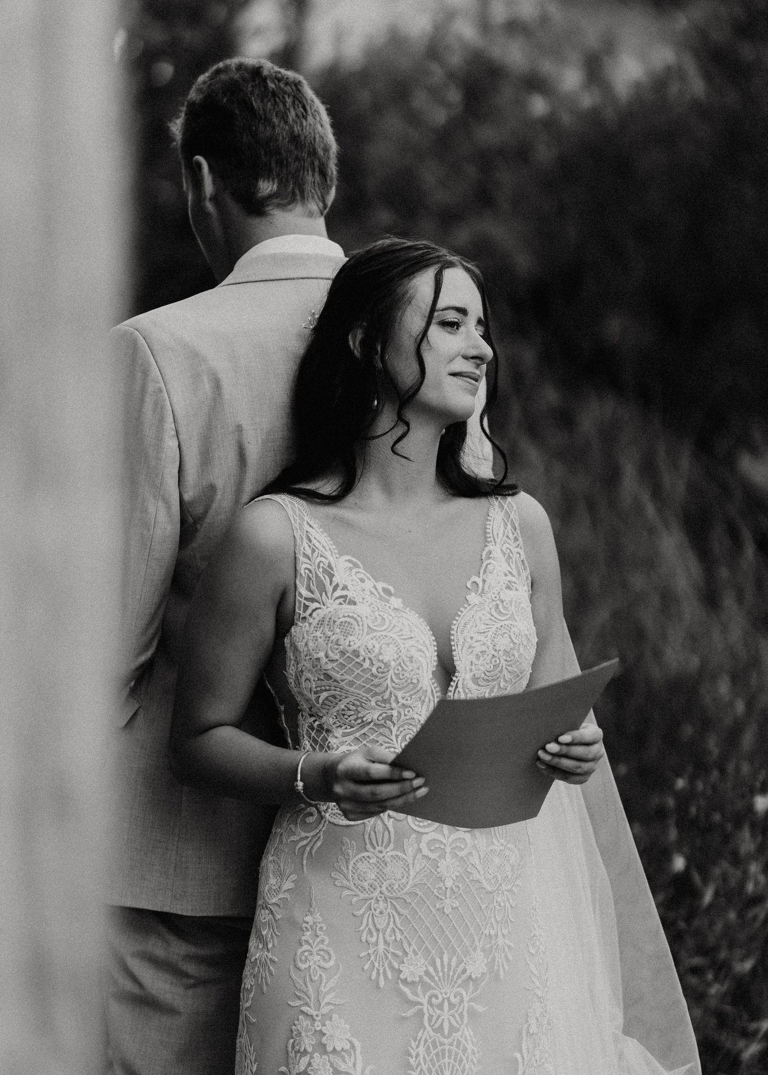 Black and white image of couple during first look reading vows while standing back to back.