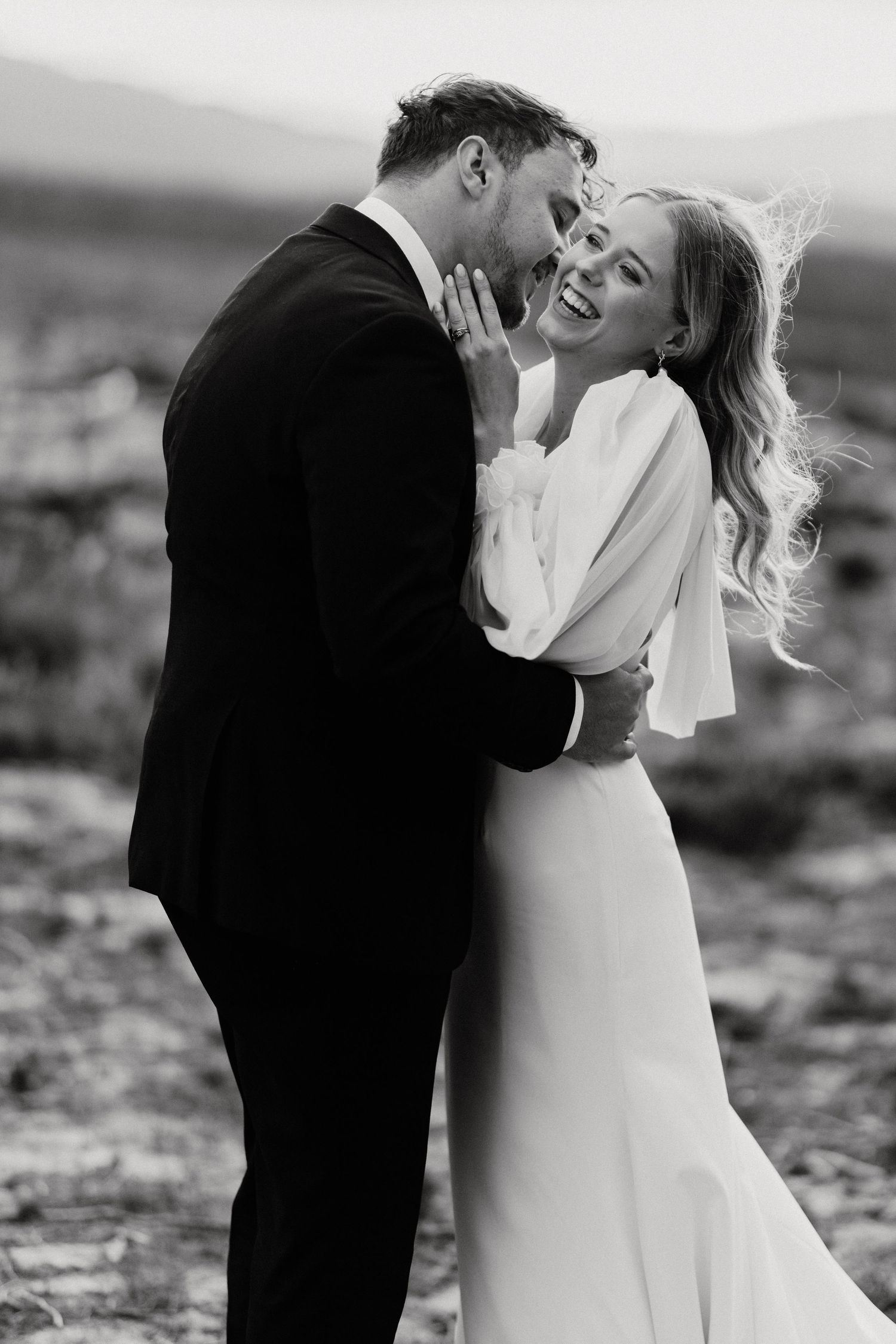 Black and white intimate portrait of newlyweds sharing tender moment outdoors.