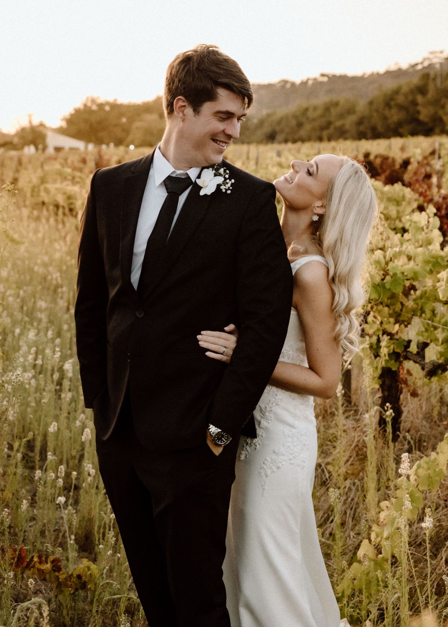 A joyful wedding moment captured in a sunlit vineyard during golden hour.