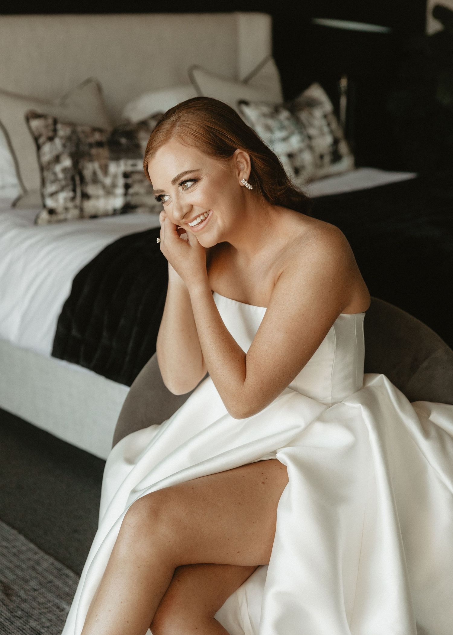 A bridal portrait showing a strapless white gown in a modern bedroom setting.
