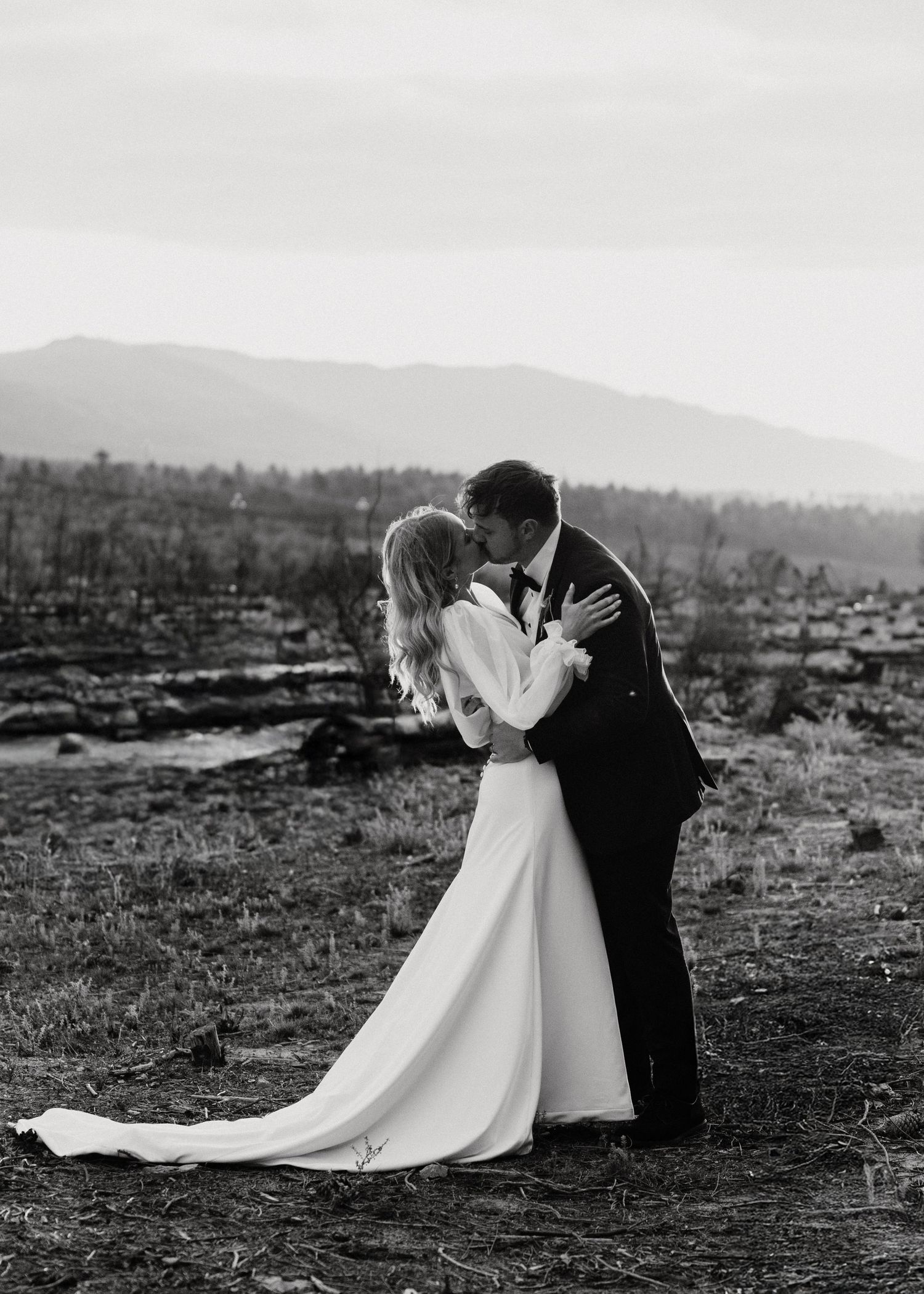 Black and white wedding portrait captures intimate moment in mountain landscape.