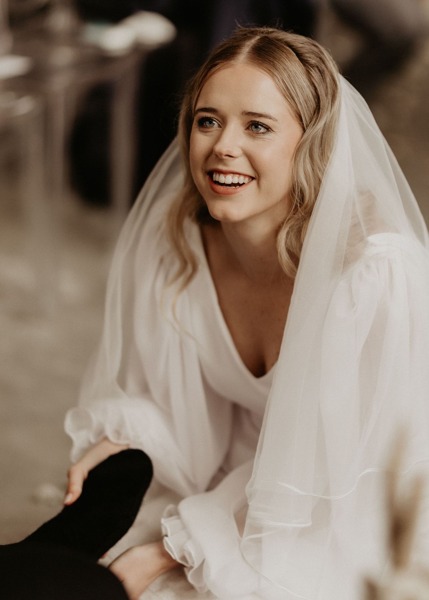 A radiant bride in a white dress and veil smiling brightly during her wedding day.