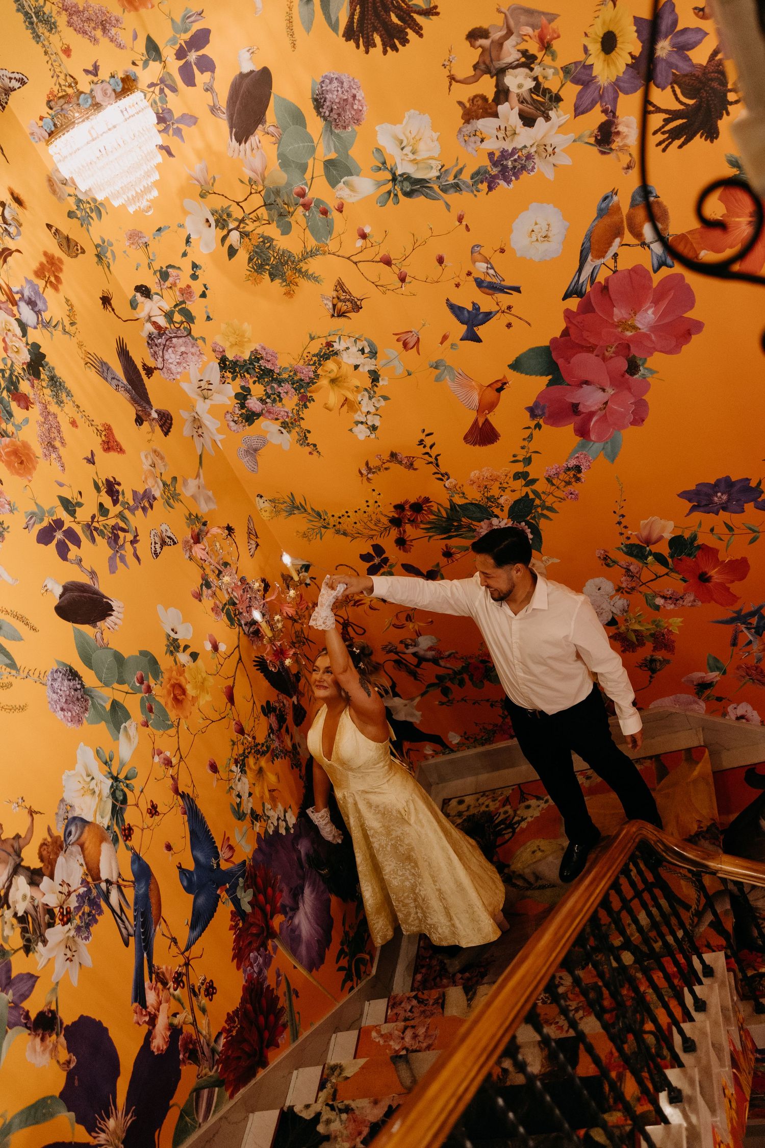 Colorful artistic mural featuring floral and bird motifs painted on an orange wall in an ornate decorative style.