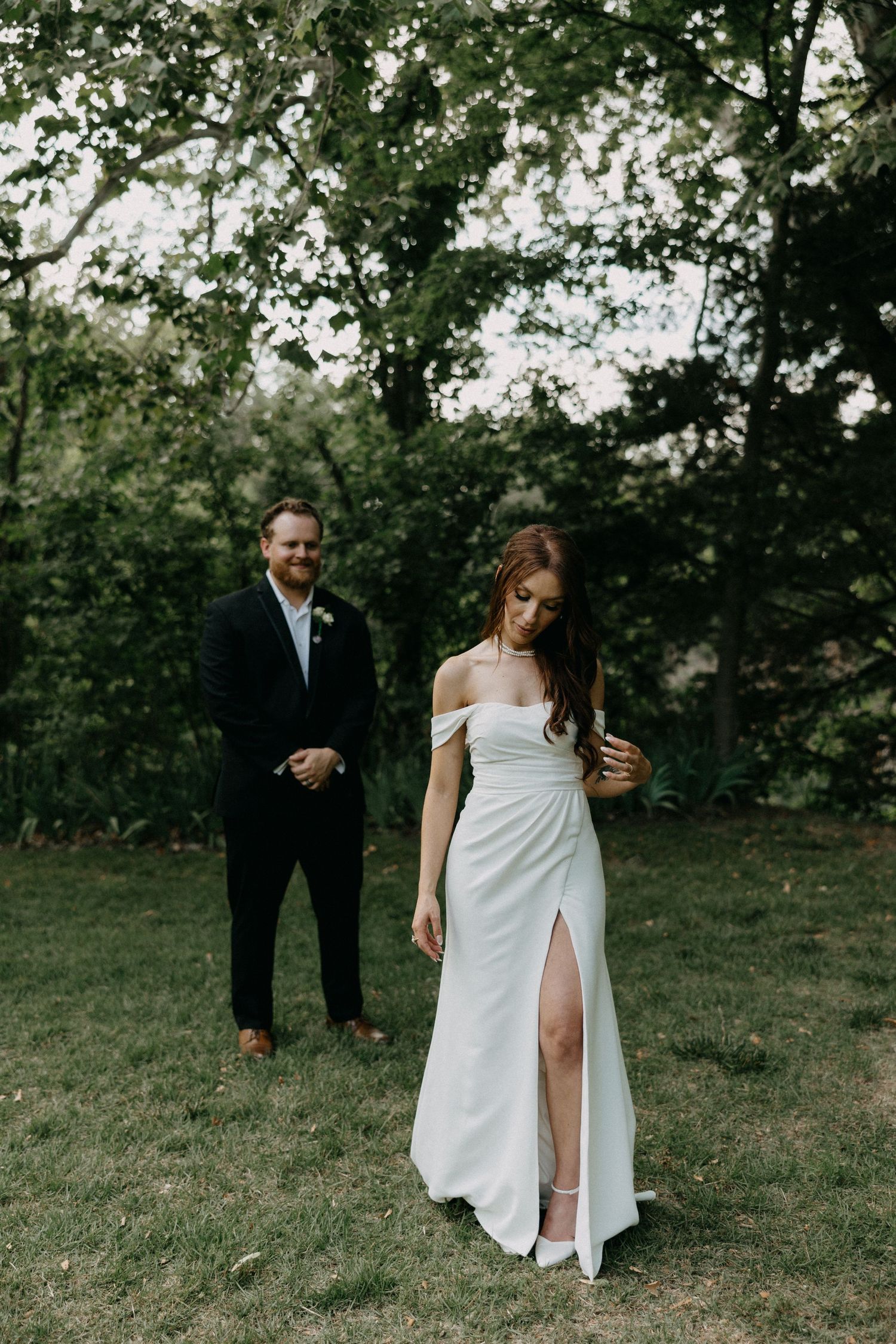 An intimate outdoor wedding portrait in a garden setting with natural greenery.