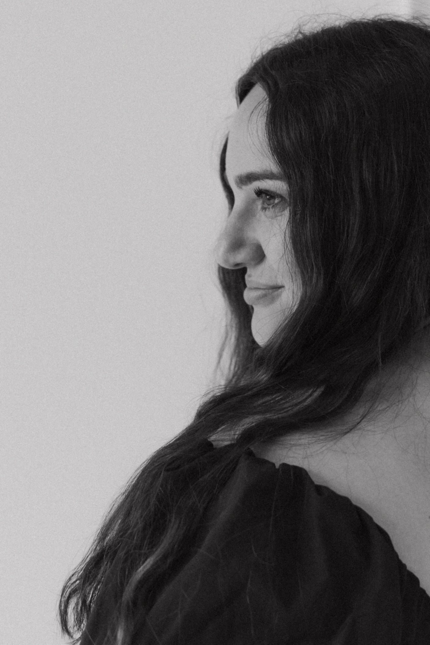 Black and white profile portrait of person with long dark hair looking off to the side against a light background.