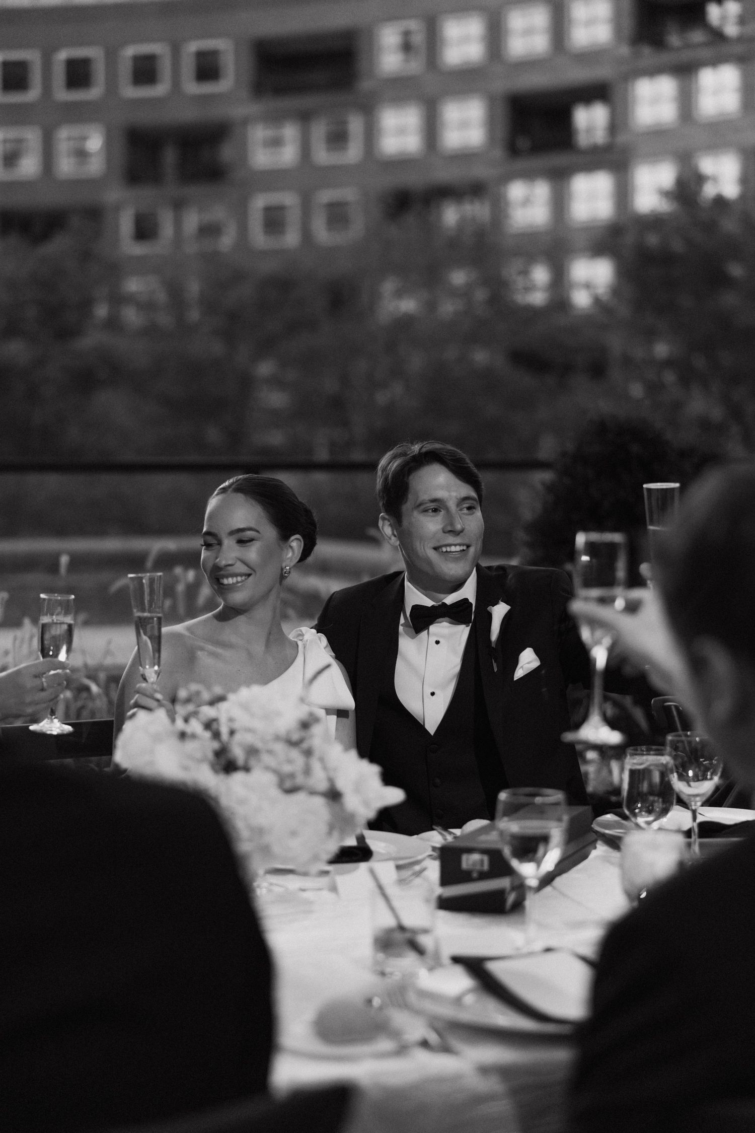 Wedding reception guests seated at tables in formal attire under ambient lighting.