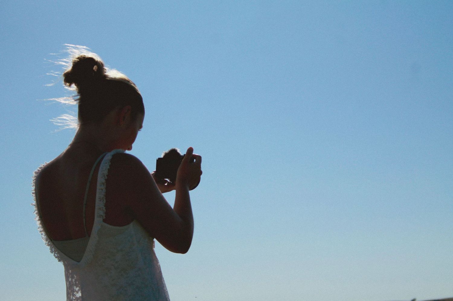 Photographer captures scenic landscape shots near a red Jeep on grassy coastal hillside.