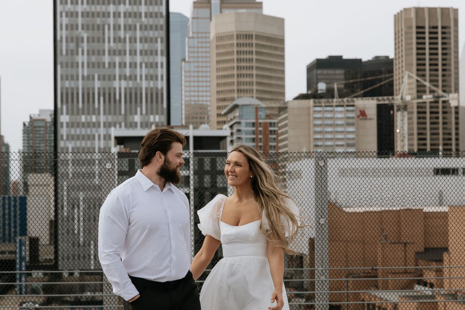 Calgary engagement photographer capturing a couple in downtown’s urban scenery with relaxed, authentic storytelling style