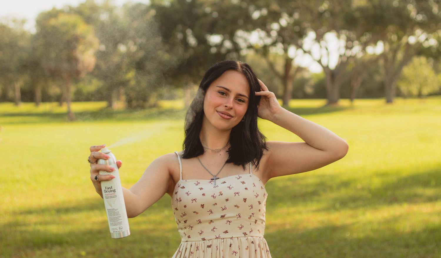 portrait of a young woman spraying hairspray