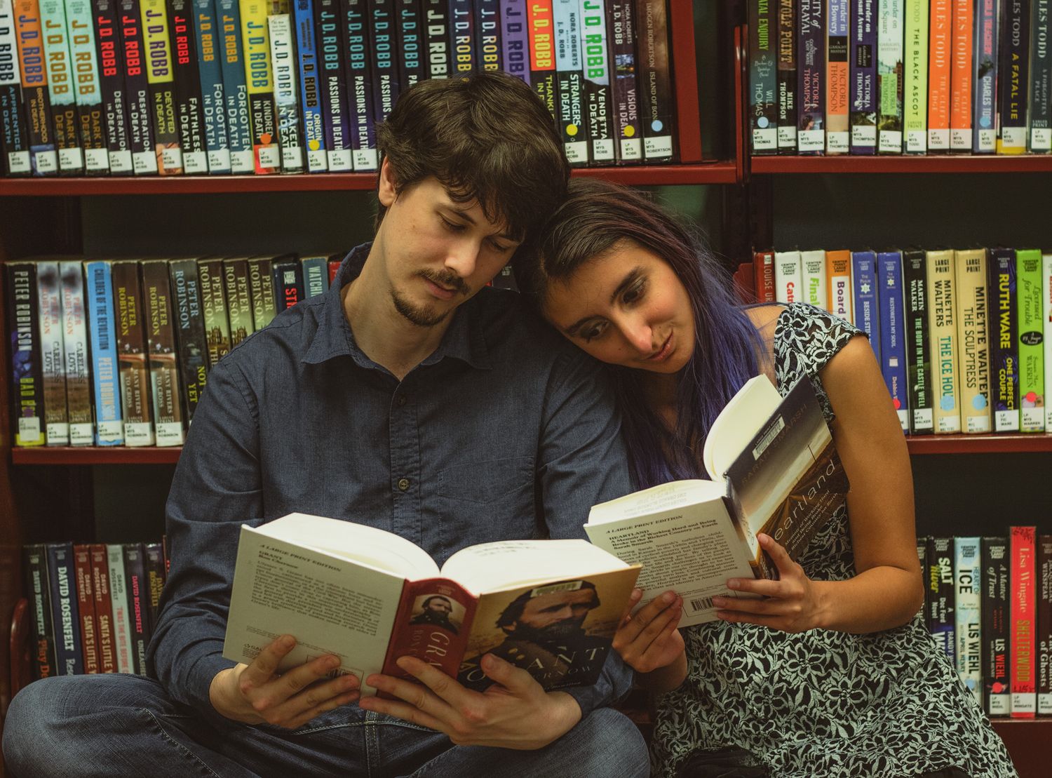 a portrait of a couple reading books in a library