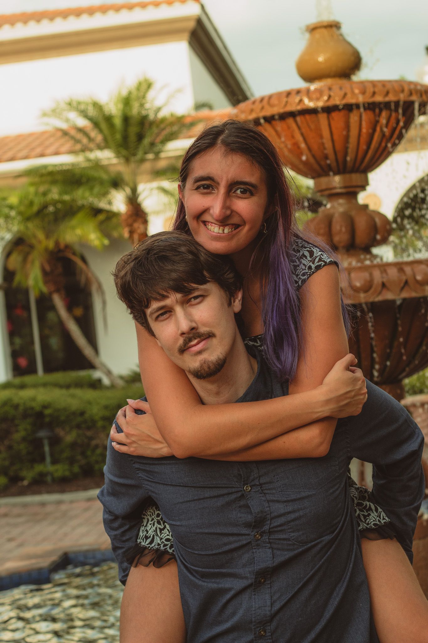 a portrait of a man giving a woman a piggy back ride smiling at the camera