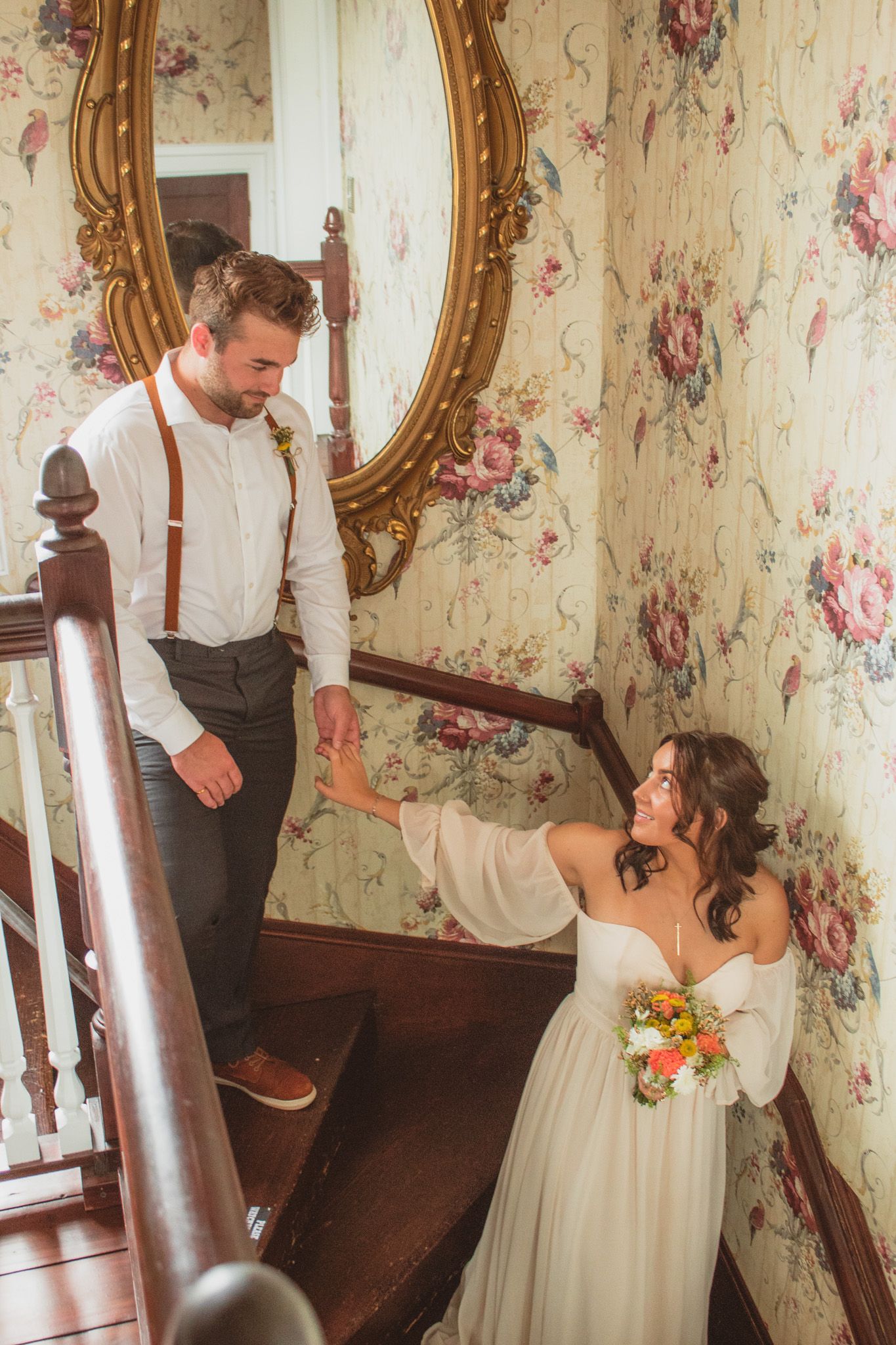 a portrait of a bride leading her groom down the stairs