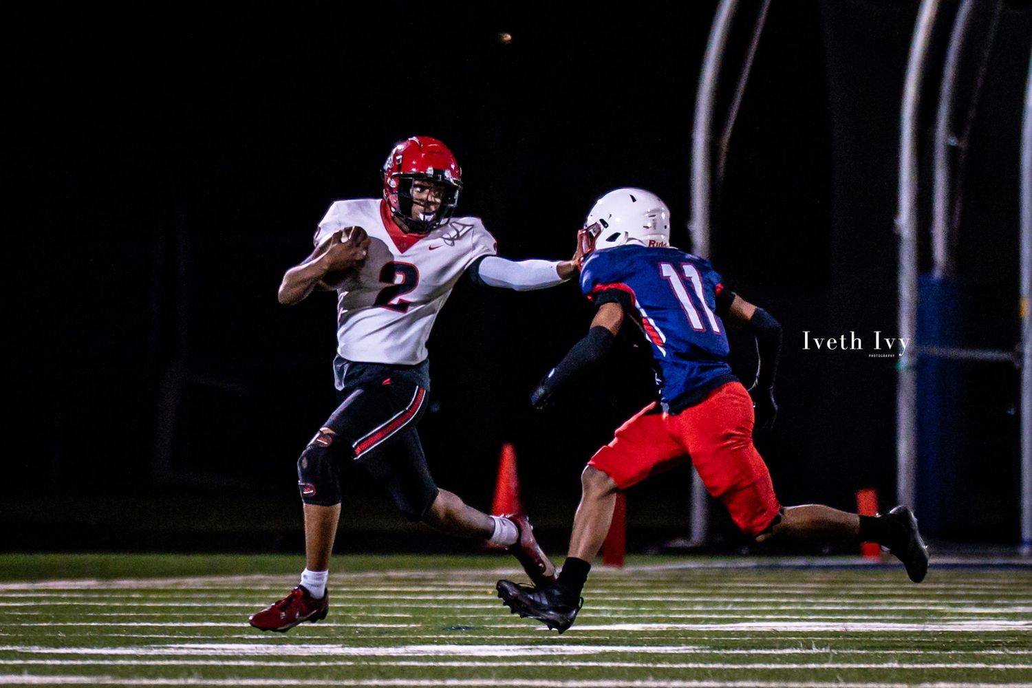 Football players in red and white uniforms make tackles during a night game on the field.