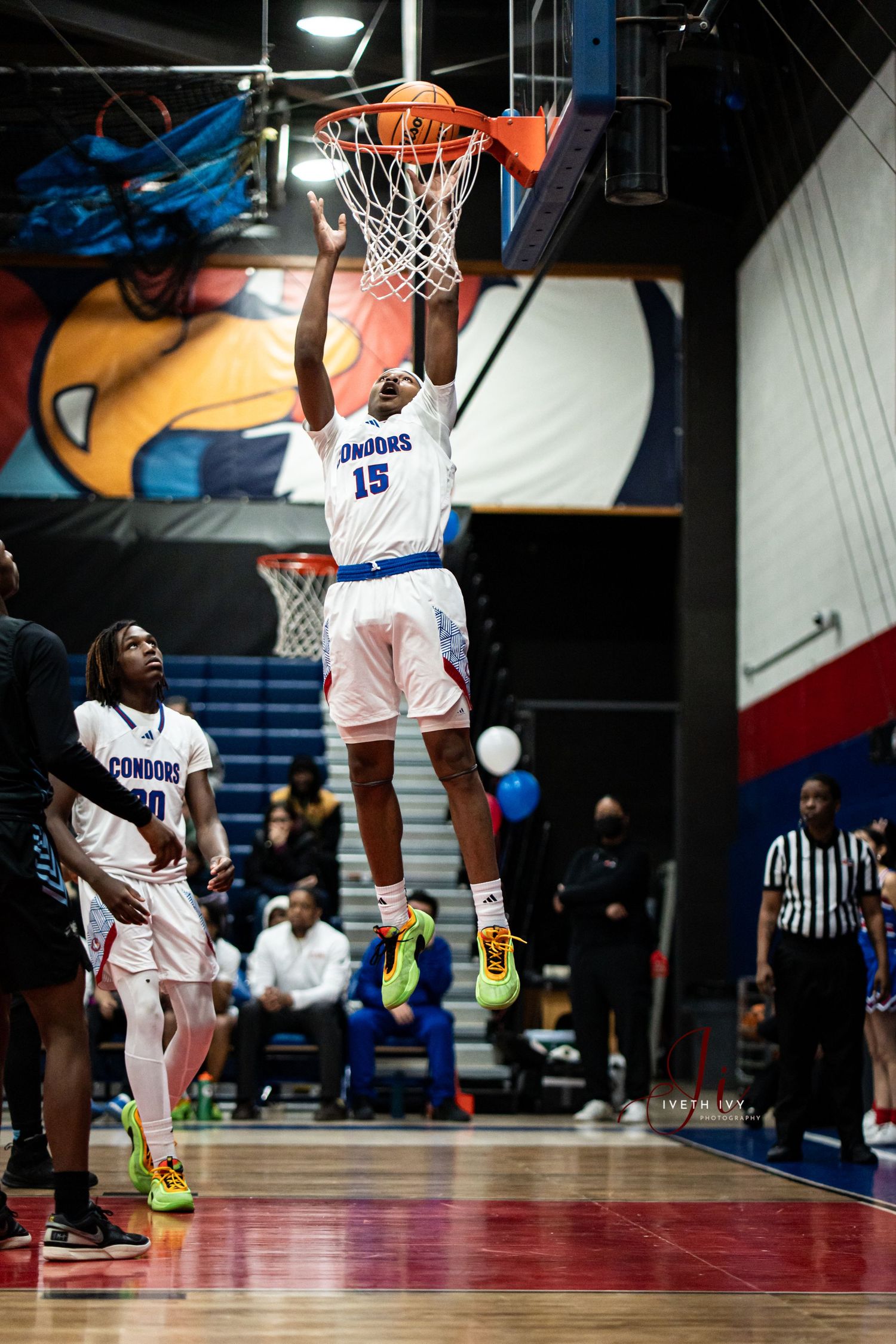 Basketball player soars through the air for a powerful slam dunk during an intense game at an indoor arena.