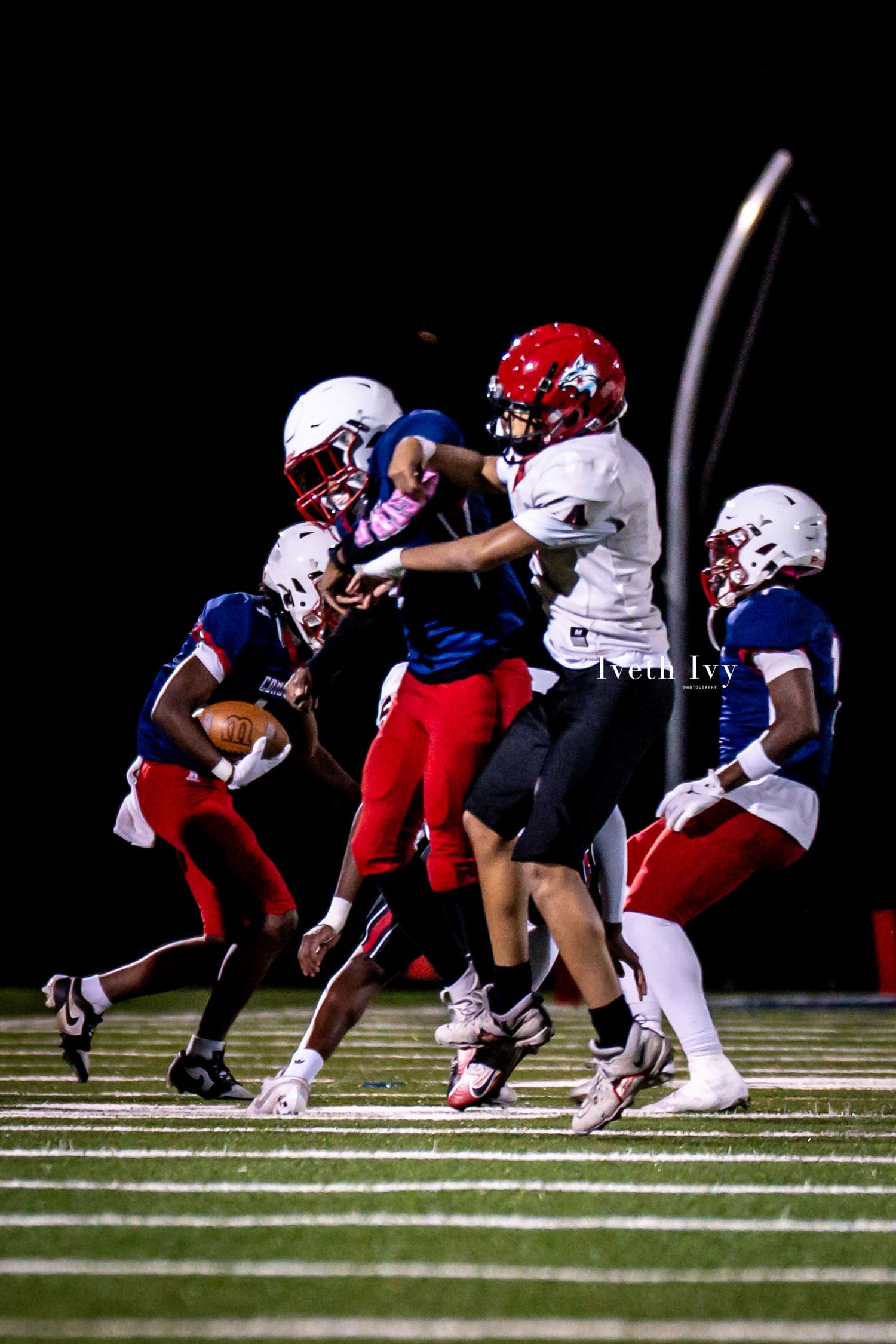 Football players from opposing teams collide during an intense tackle play on the field.