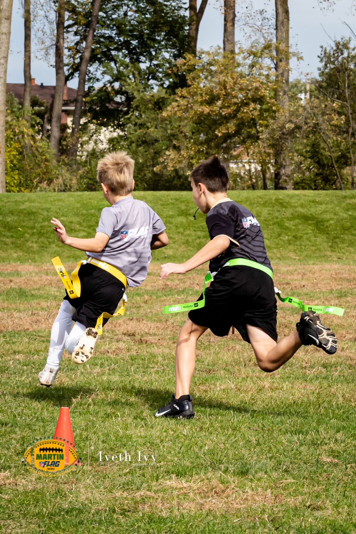 Two players dive to catch a frisbee on a grassy field during an ultimate frisbee game.