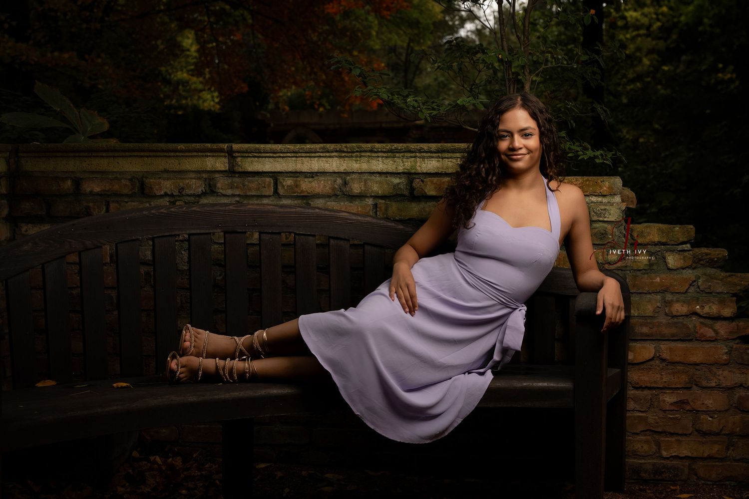 Lavender dress photographed against rustic brick wall in moody outdoor setting.