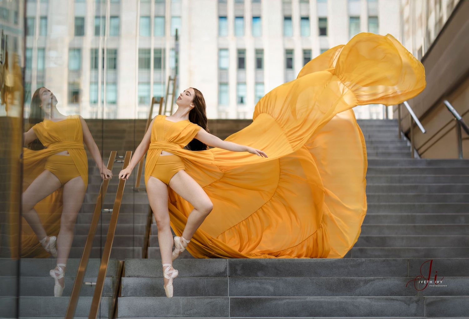 A flowing yellow dress captured in motion against urban architecture and stairs.