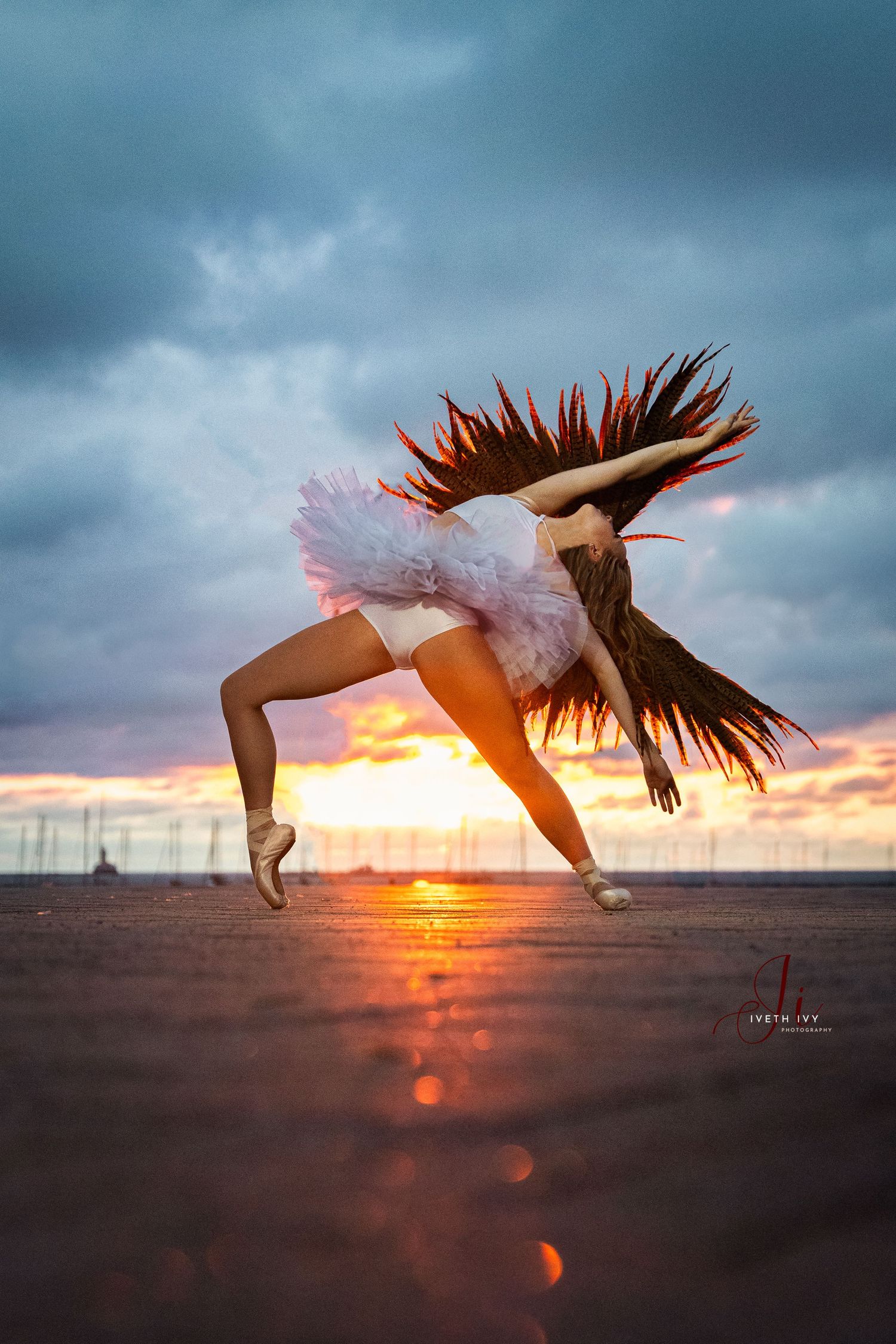Dramatic dance pose silhouette with hair motion against sunset sky.