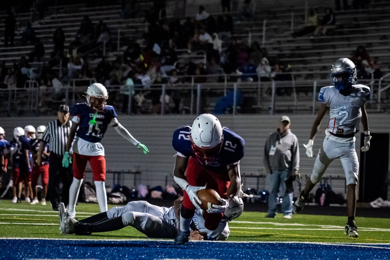 Football players collide during a tackle sequence in a high school game on the field.