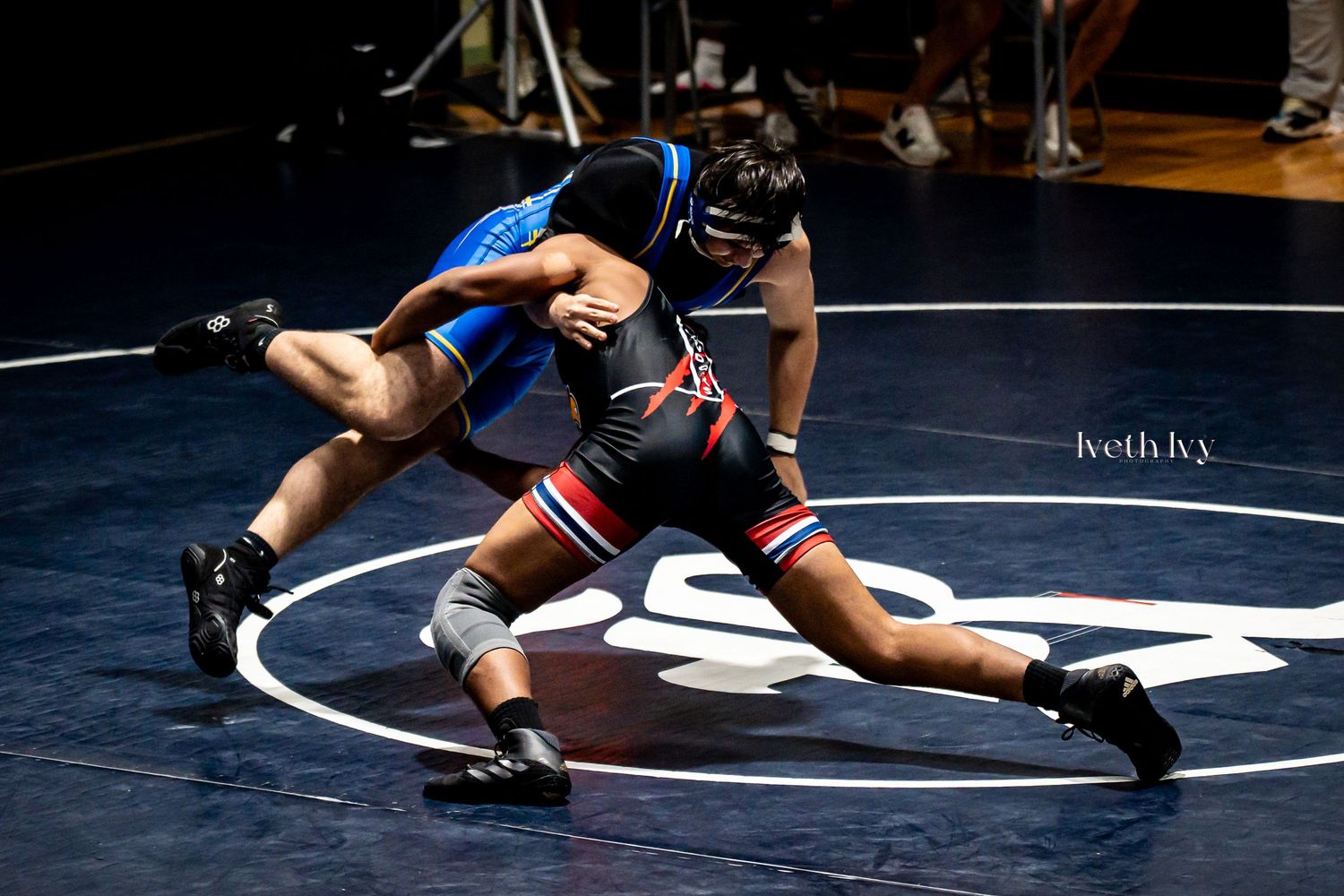 Two wrestlers engage in a competitive match on a circular wrestling mat during a tournament.